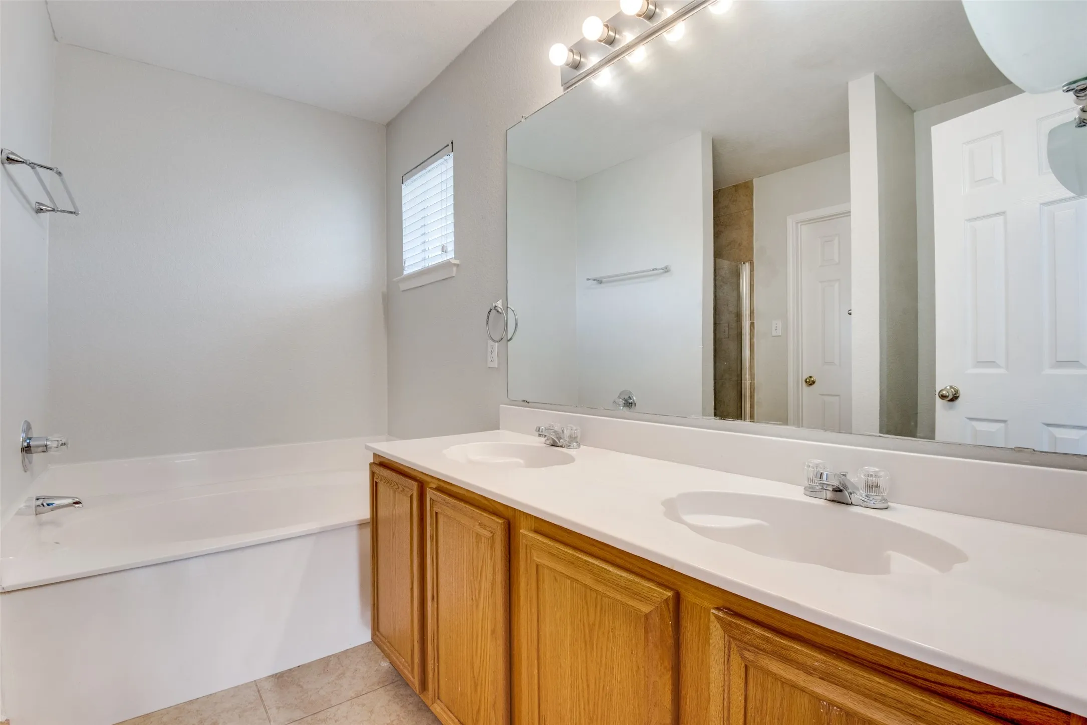 Bathroom with dual vanity, tile patterned floors, and a bathing tub