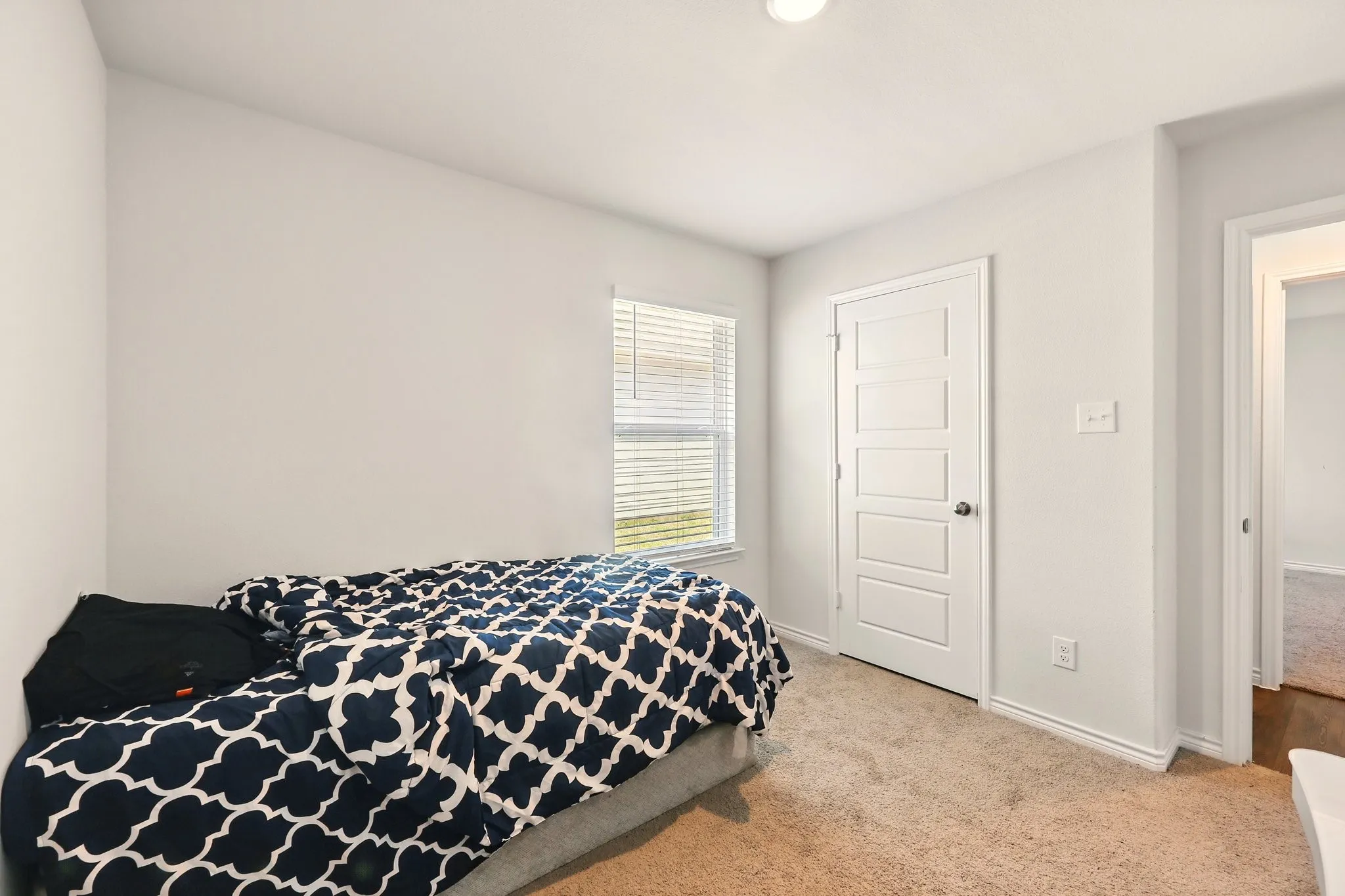 Neutral wall paint, window with blinds, paneled interior door, and carpet flooring