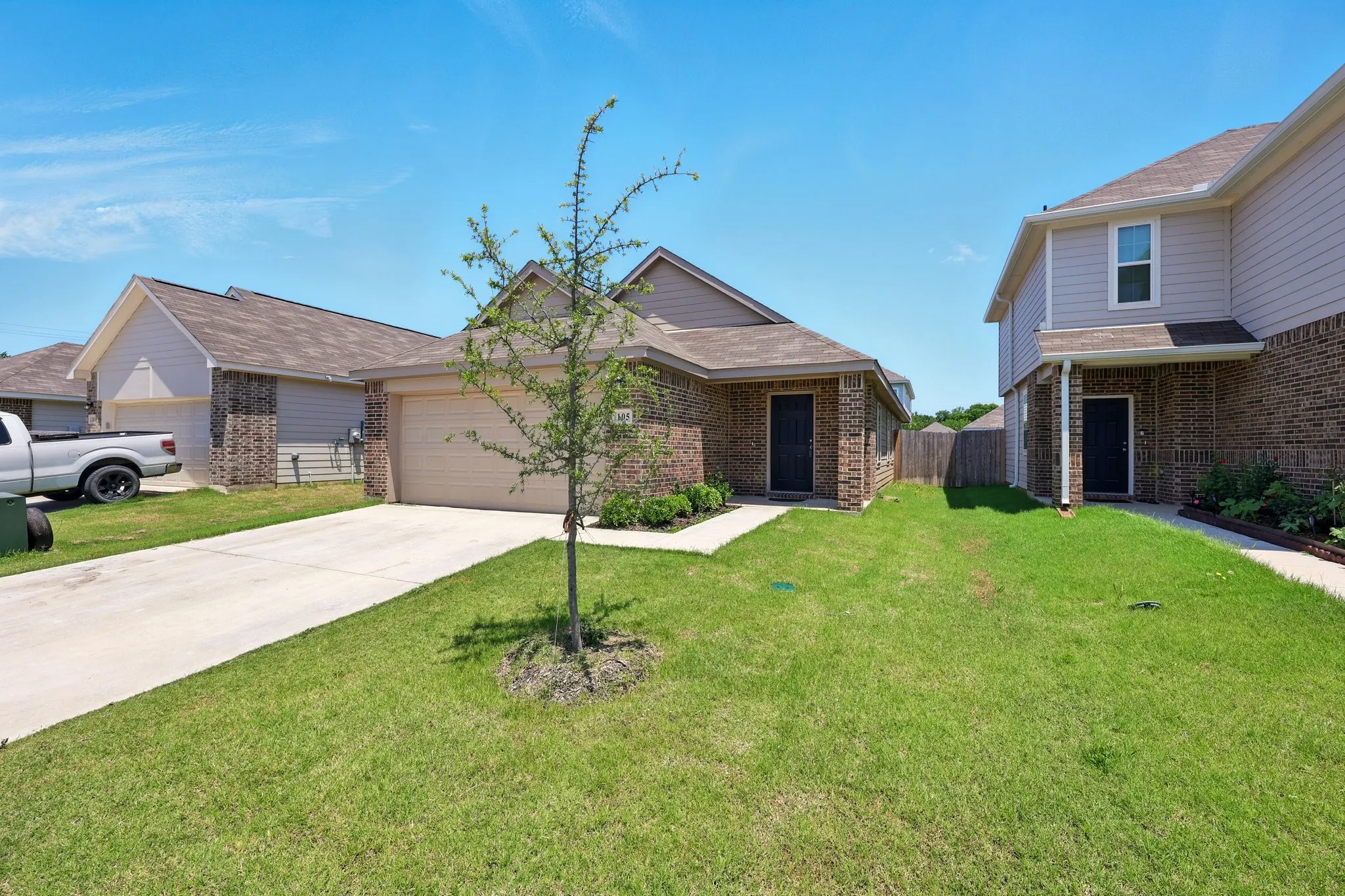 Brick and siding exterior with a concrete driveway, attached garage, and a lush front lawn