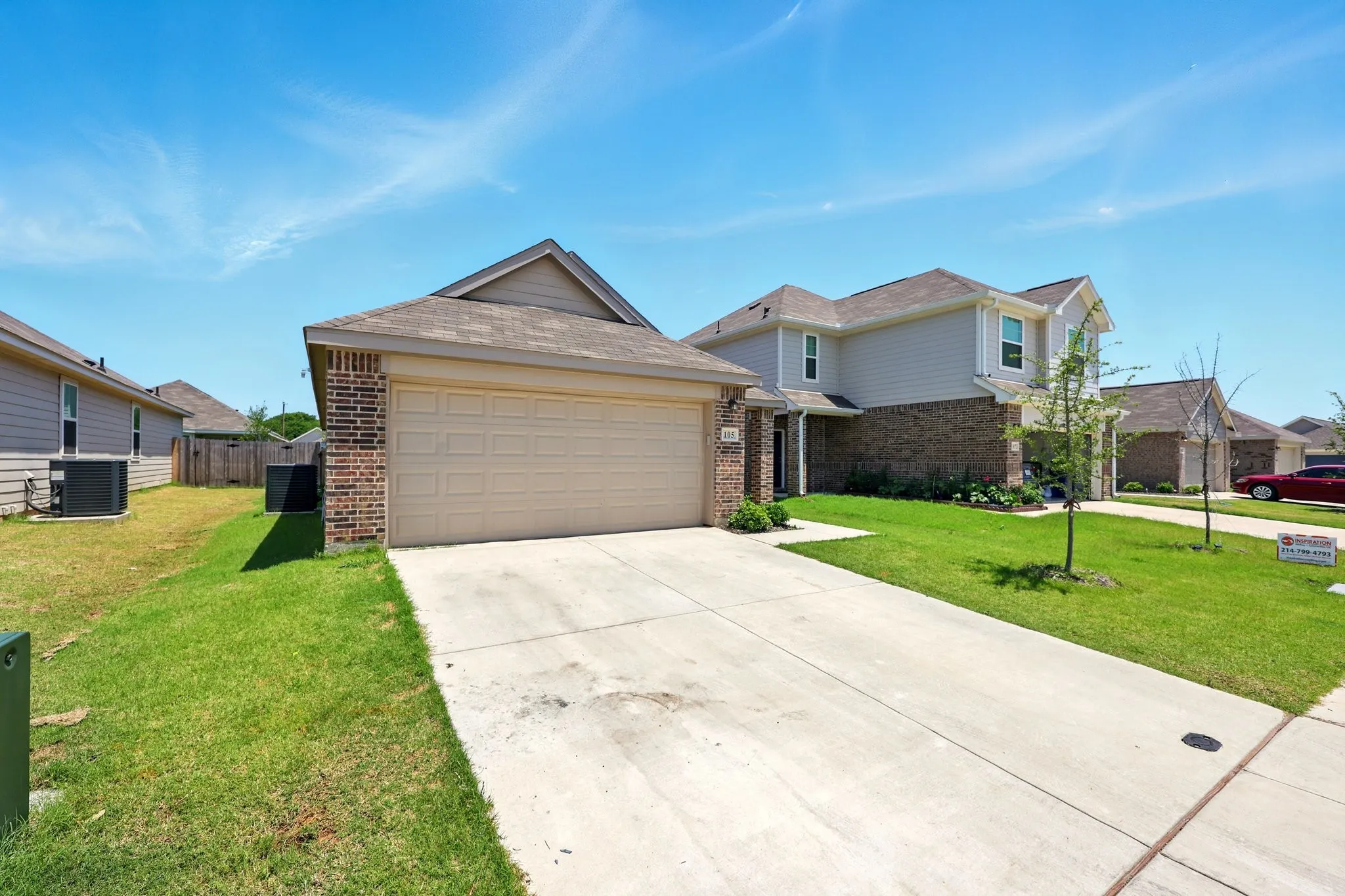 Brick and siding exterior with an attached garage, concrete driveway, and a front lawn
