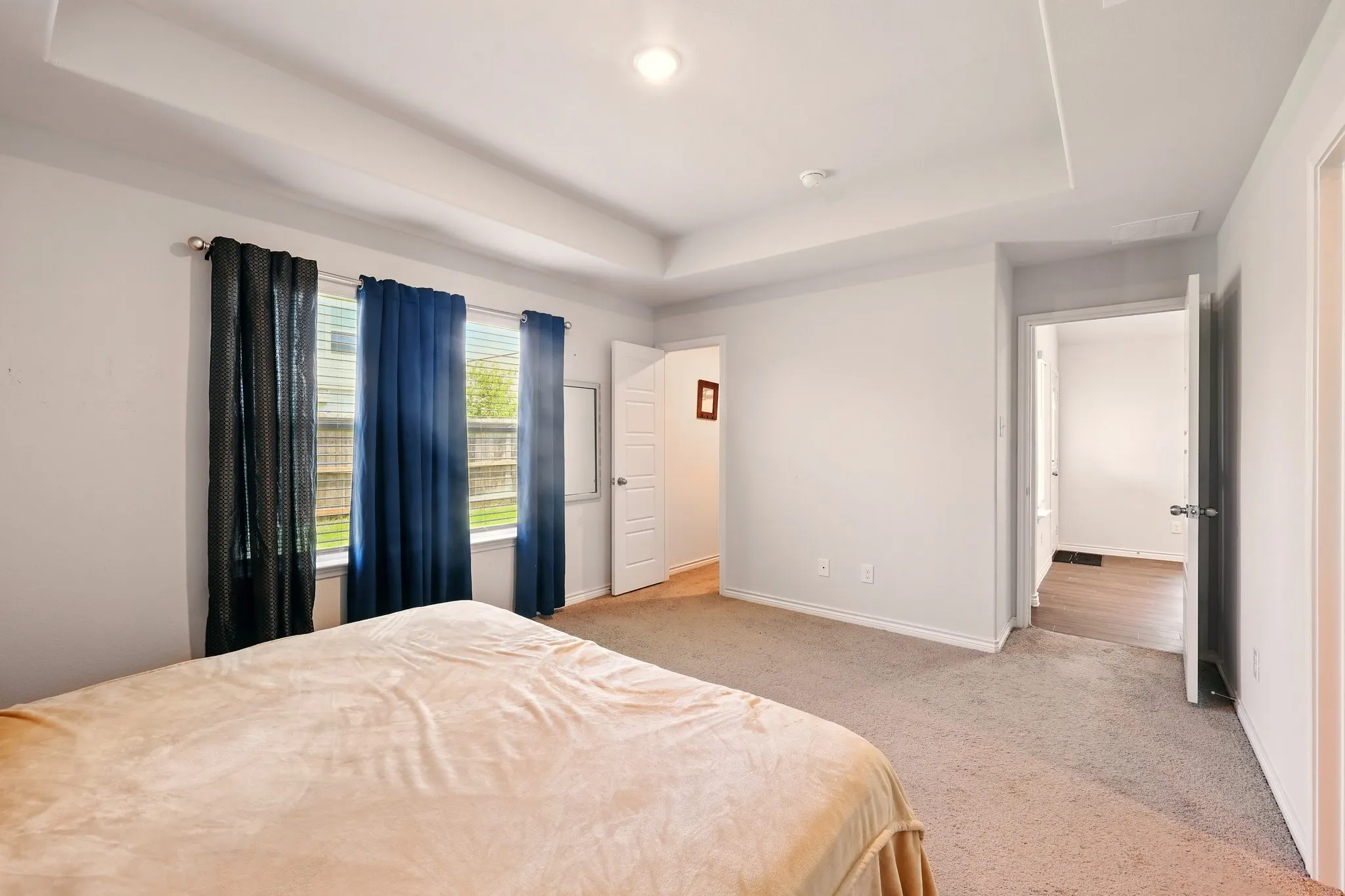 Tray ceiling with recessed lighting and neutral carpet flooring