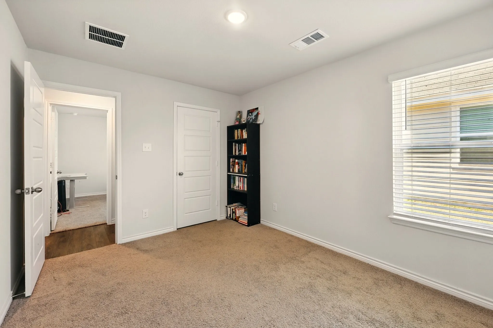 Carpeted interior space with a window featuring horizontal blinds, recessed lighting, and a paneled door