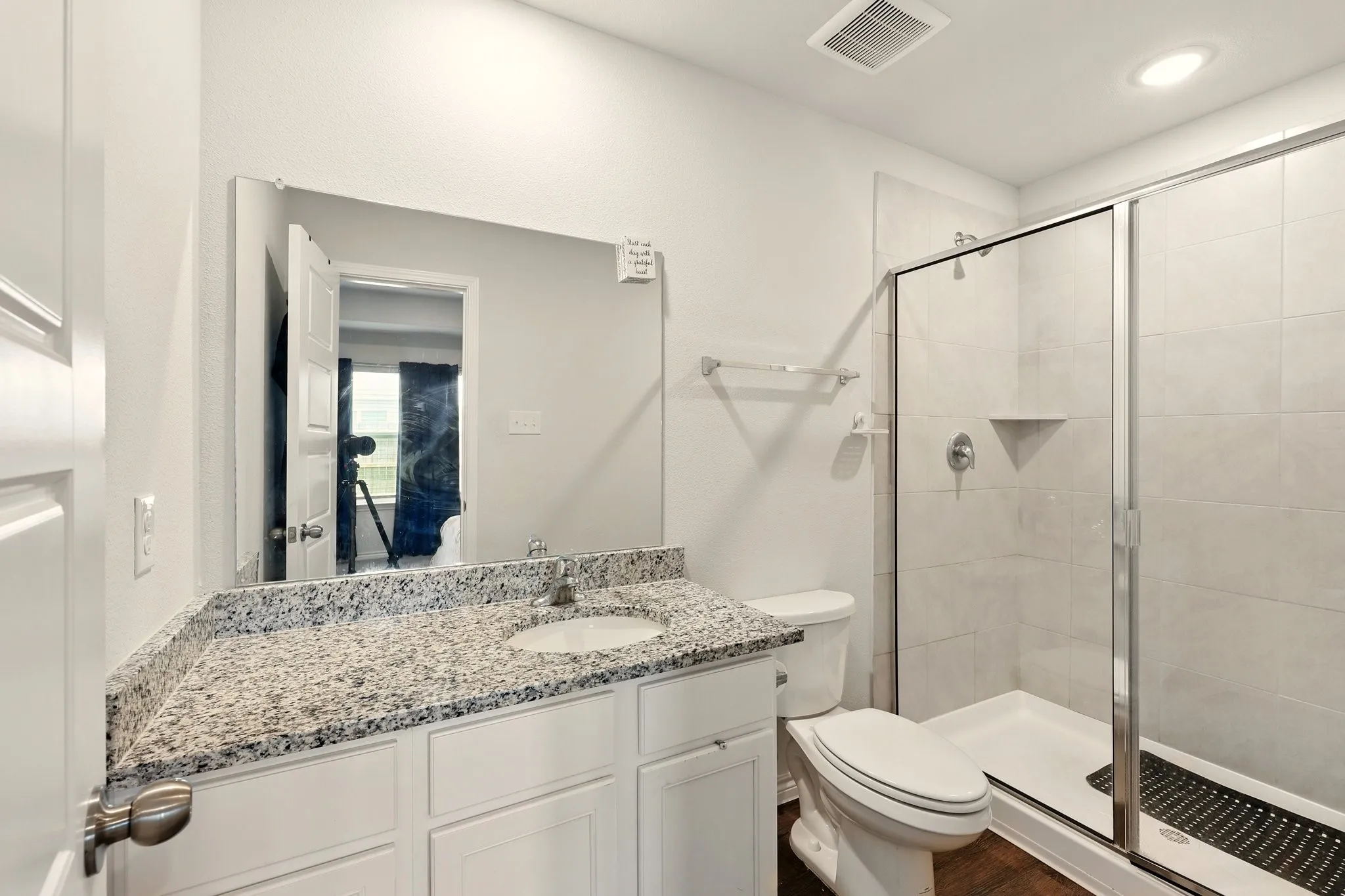 White shaker vanity with a speckled countertop and integrated sink