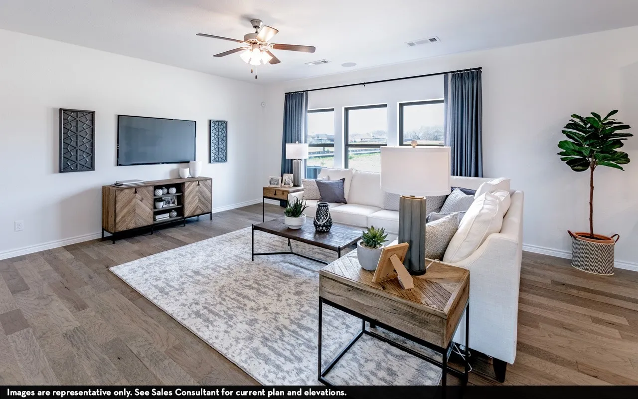 Spacious living area featuring wood-finish flooring, ample natural light from multiple windows, a ceiling fan, and recessed lighting