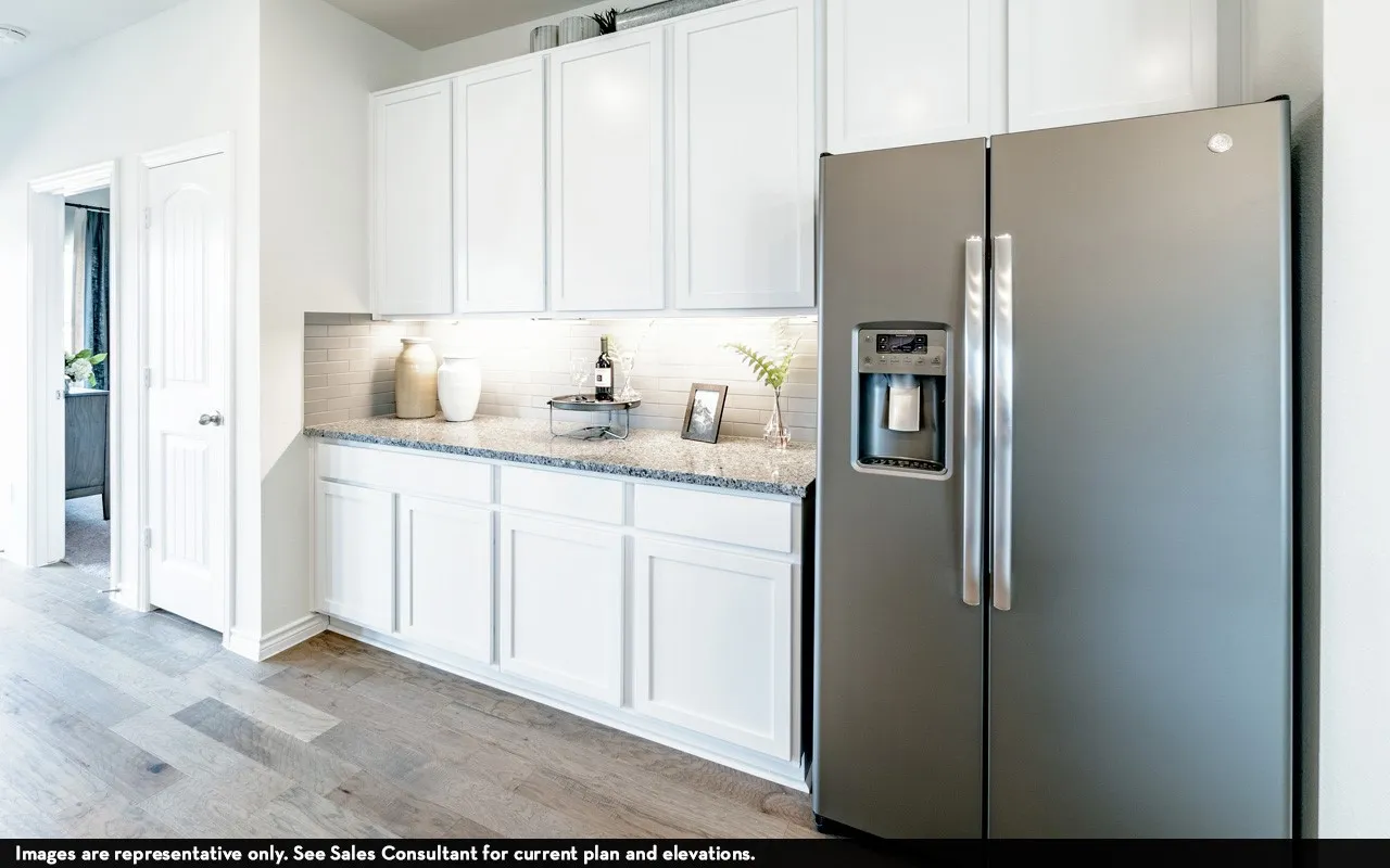 White shaker cabinetry, light-toned wood-finish flooring, stainless steel side-by-side refrigerator, speckled countertop, and white subway tile backsplash