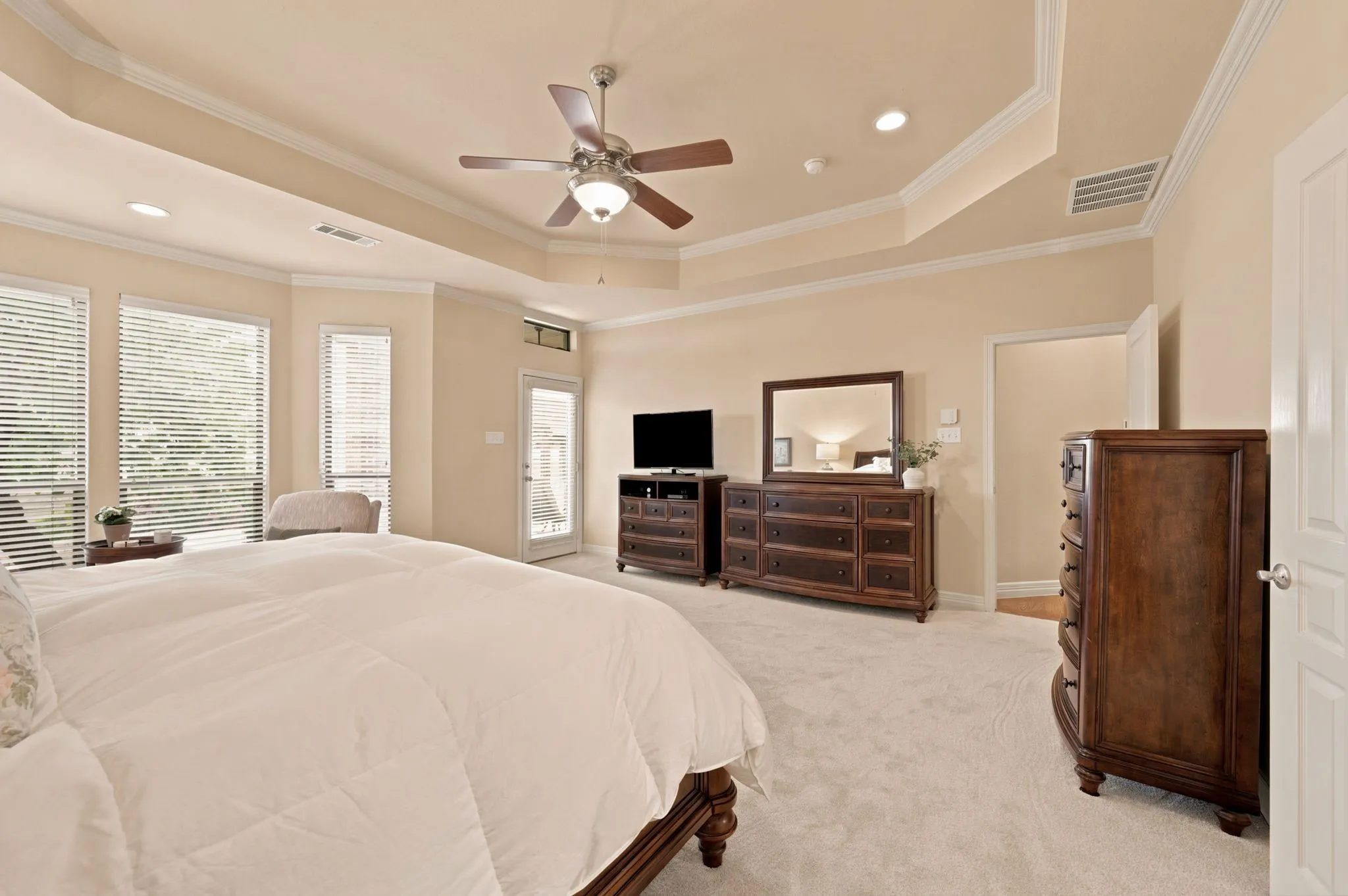 Expansive room featuring a tray ceiling with crown molding, ceiling fan, and recessed lighting