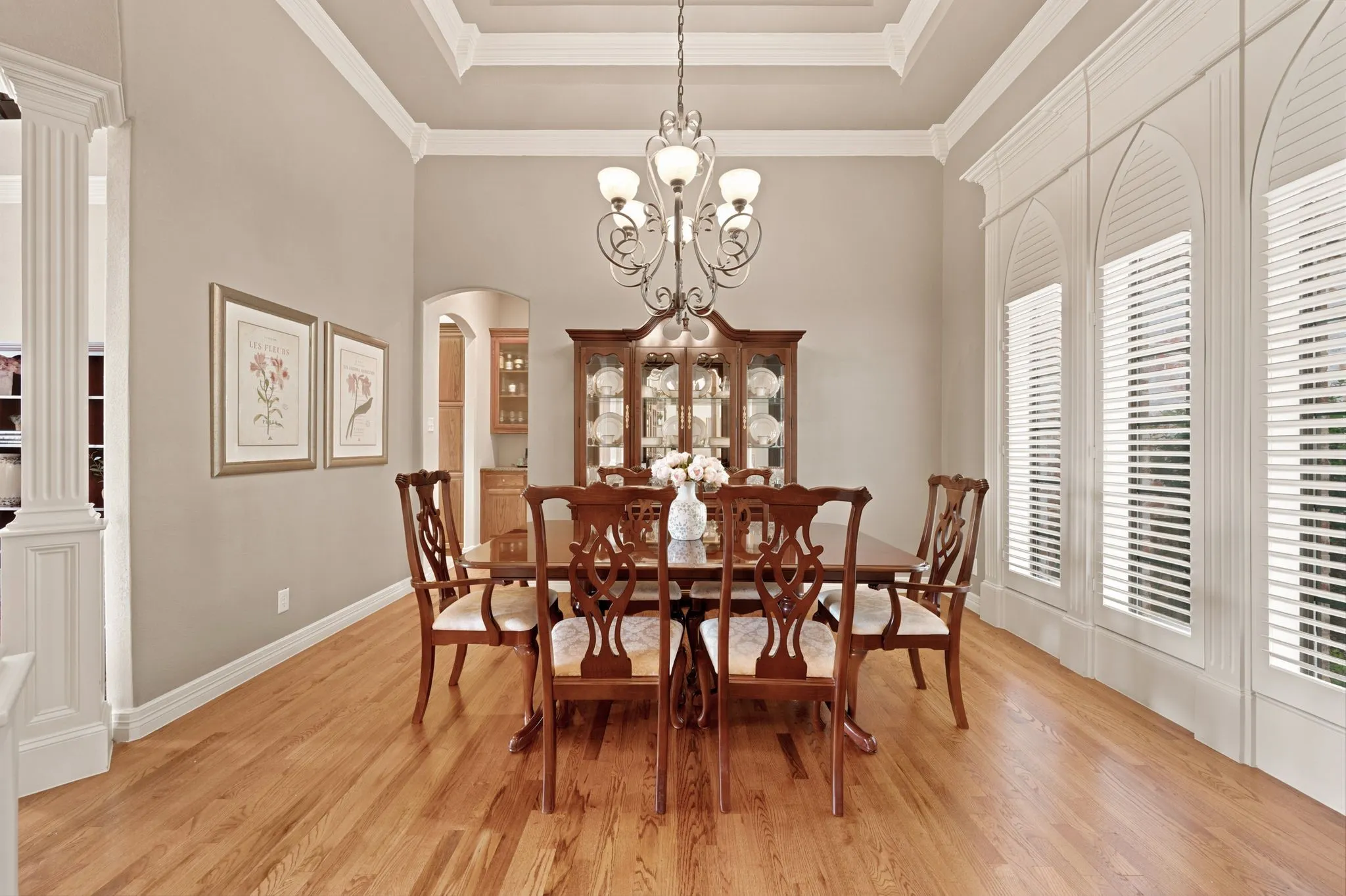 Formal dining area featuring wood-finish flooring, a tray ceiling with crown molding, and an ornate chandelier