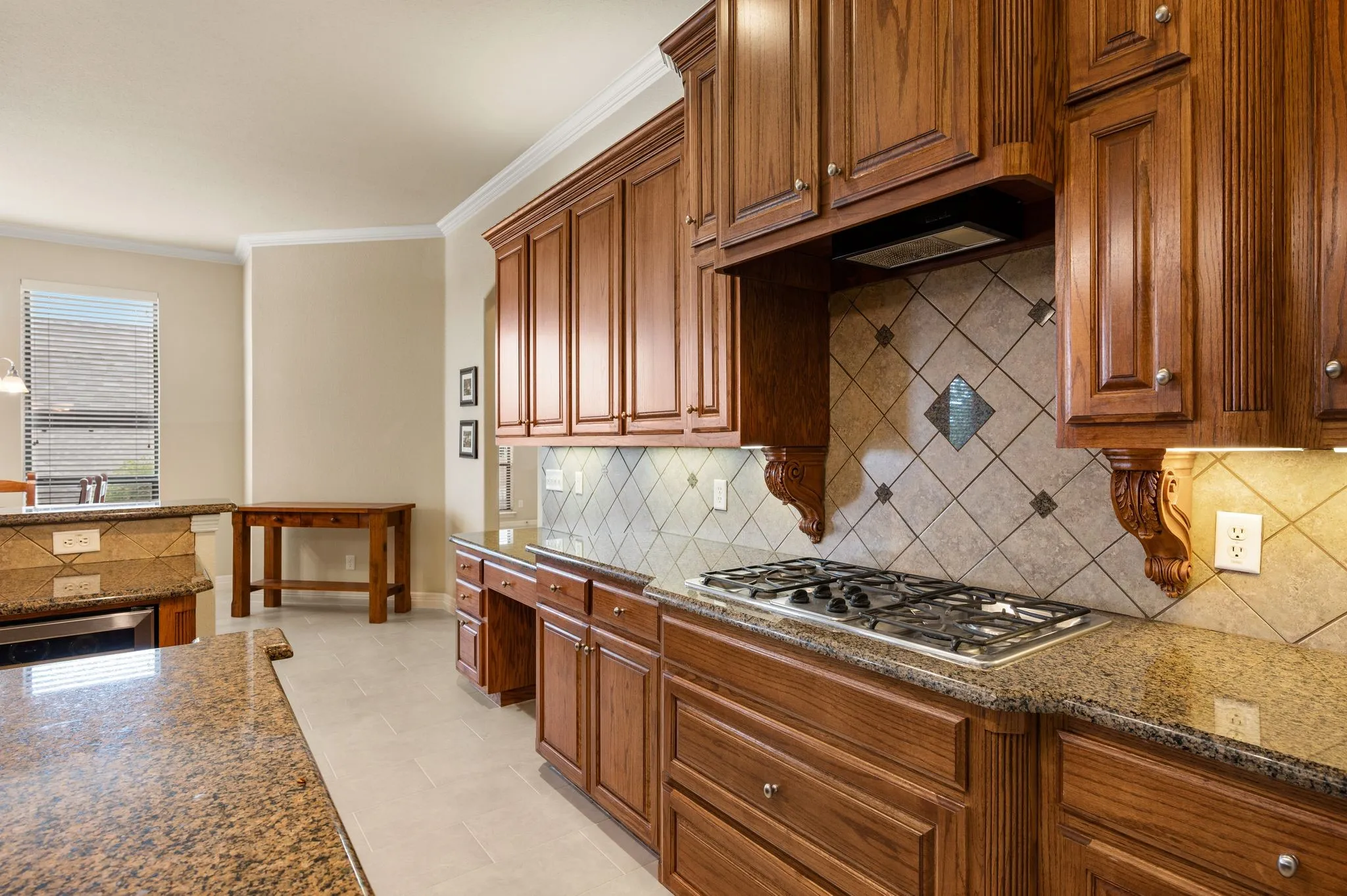 Kitchen featuring cabinetry with crown molding and decorative corbels, stone-finish countertops, diagonal-set tile backsplash, built-in gas cooktop, and tile flooring