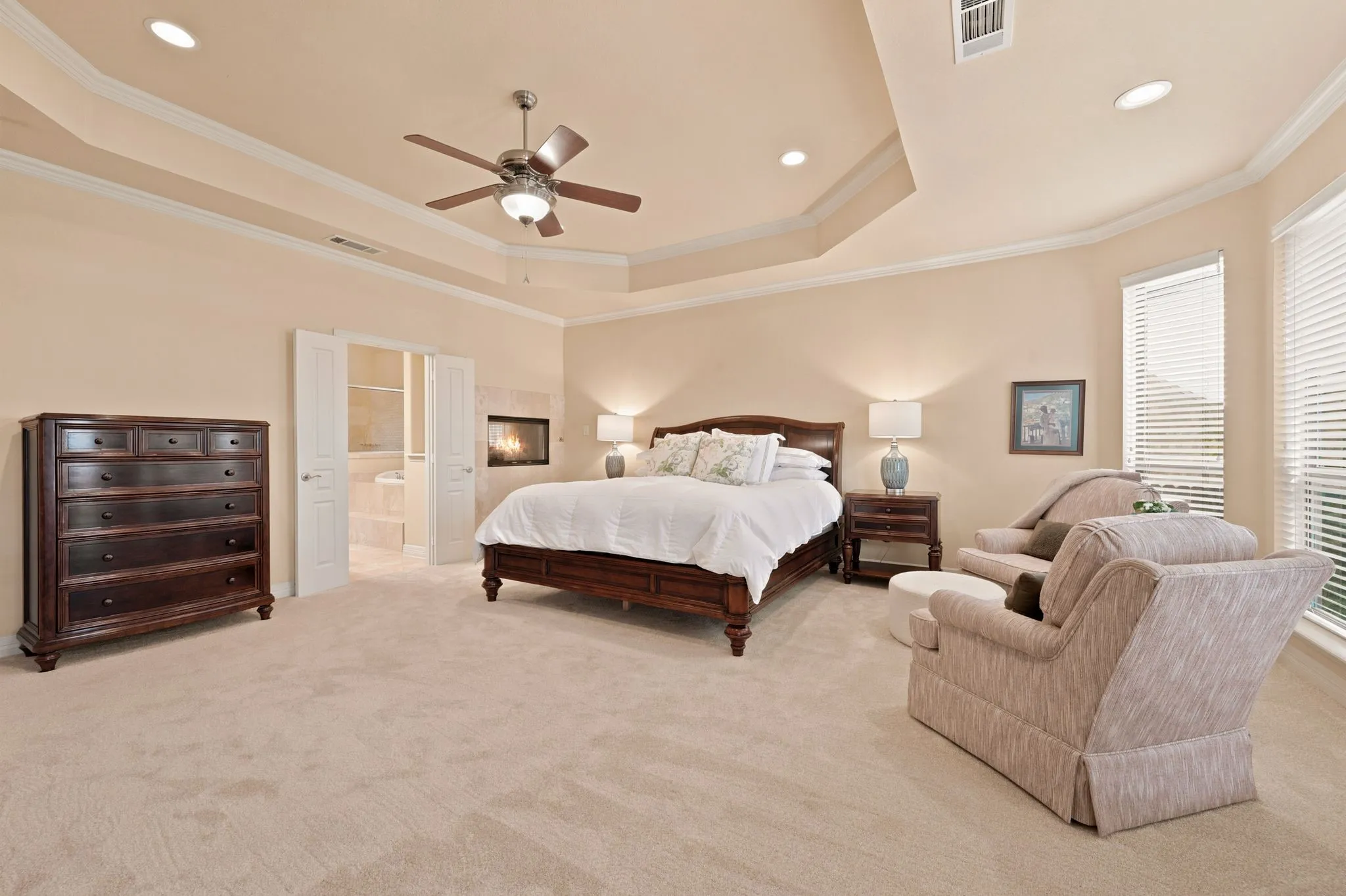 Spacious room featuring tray ceilings with crown molding, recessed lighting, and a ceiling fan