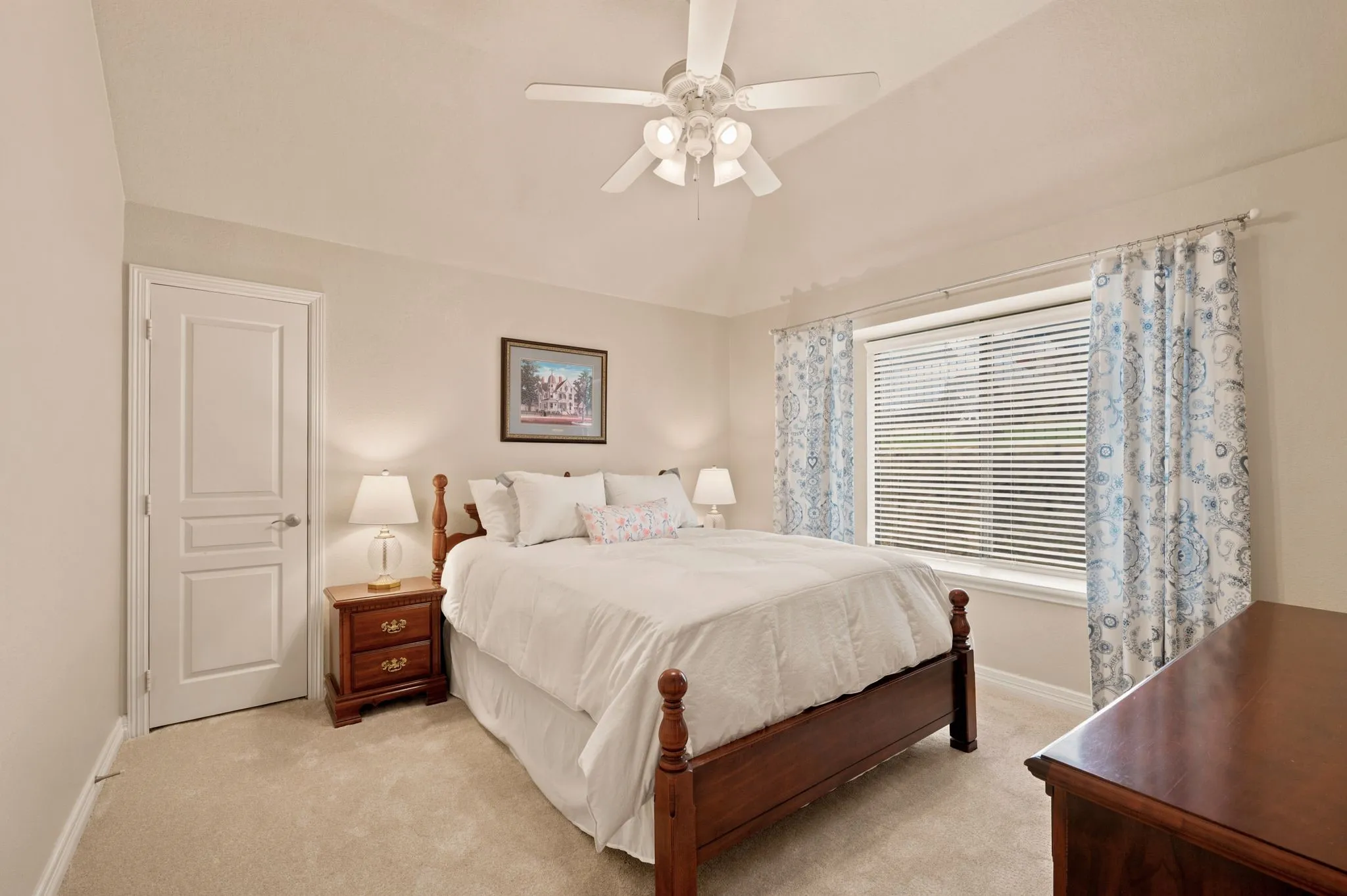 Vaulted ceiling bedroom featuring a ceiling fan, light neutral-toned carpeting, white trim, and a window with blinds