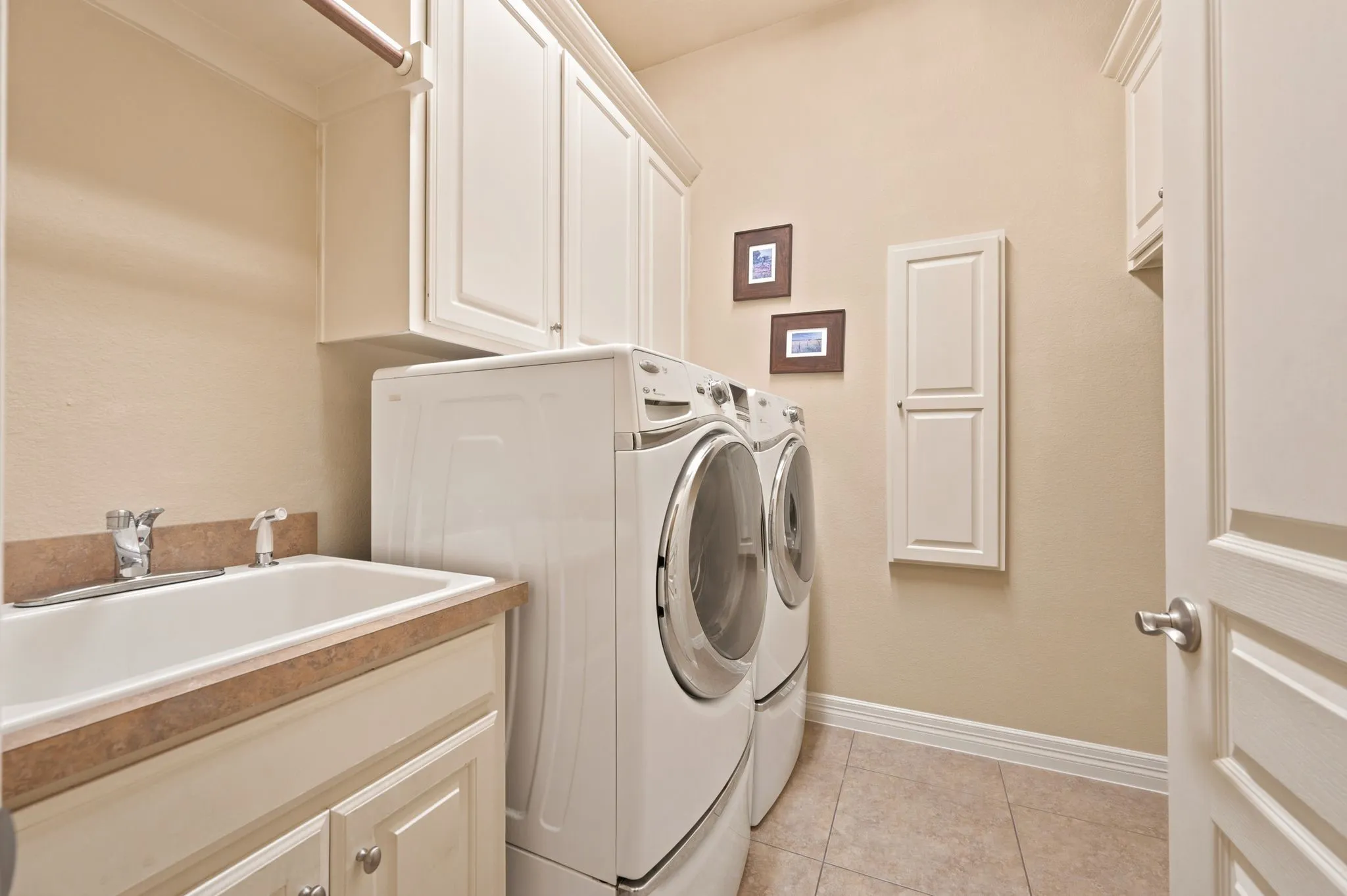 Utility room featuring a utility sink, light-toned countertop, and extensive upper and lower cabinetry