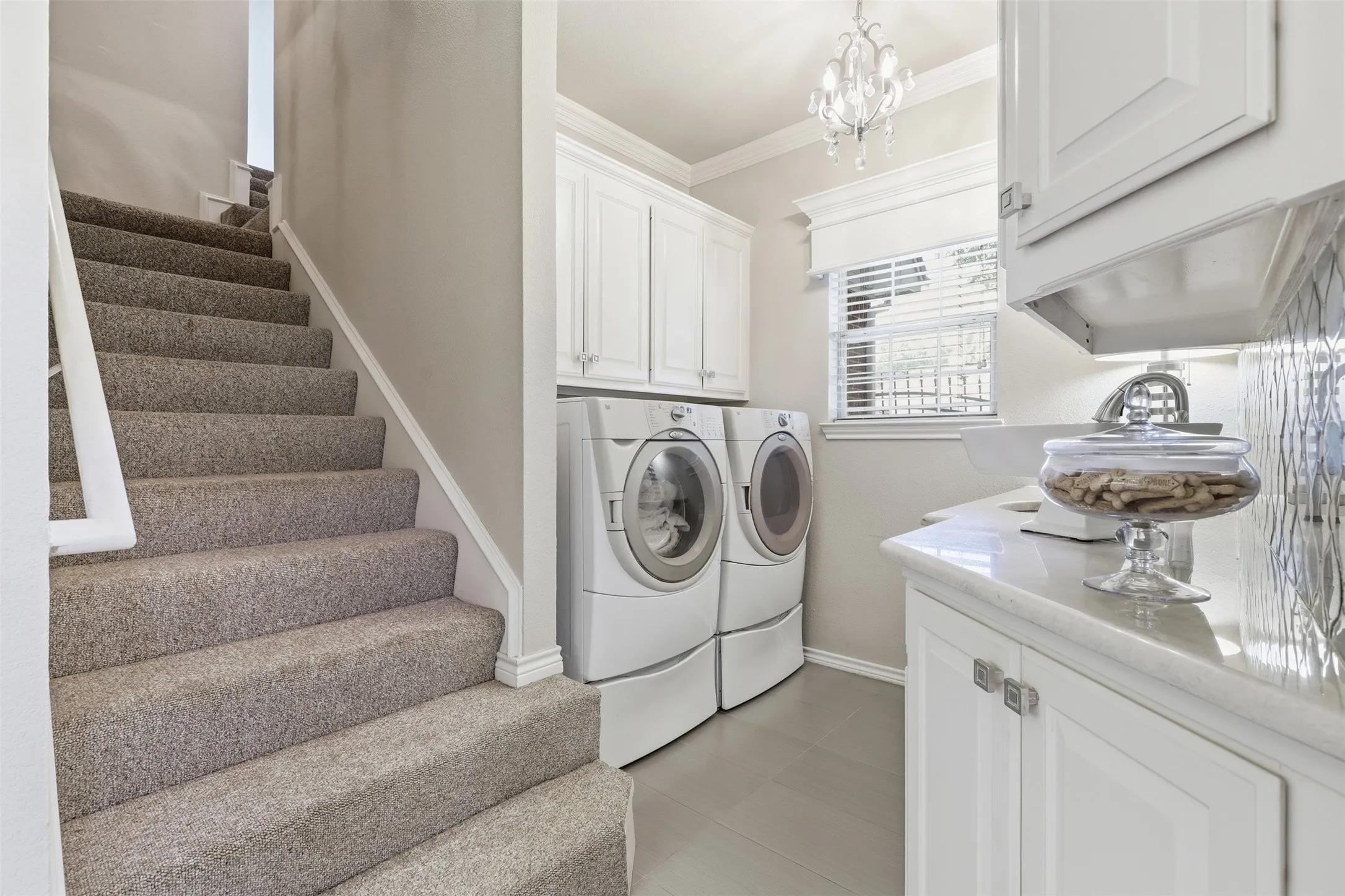 Laundry room with steps leading to bonus room