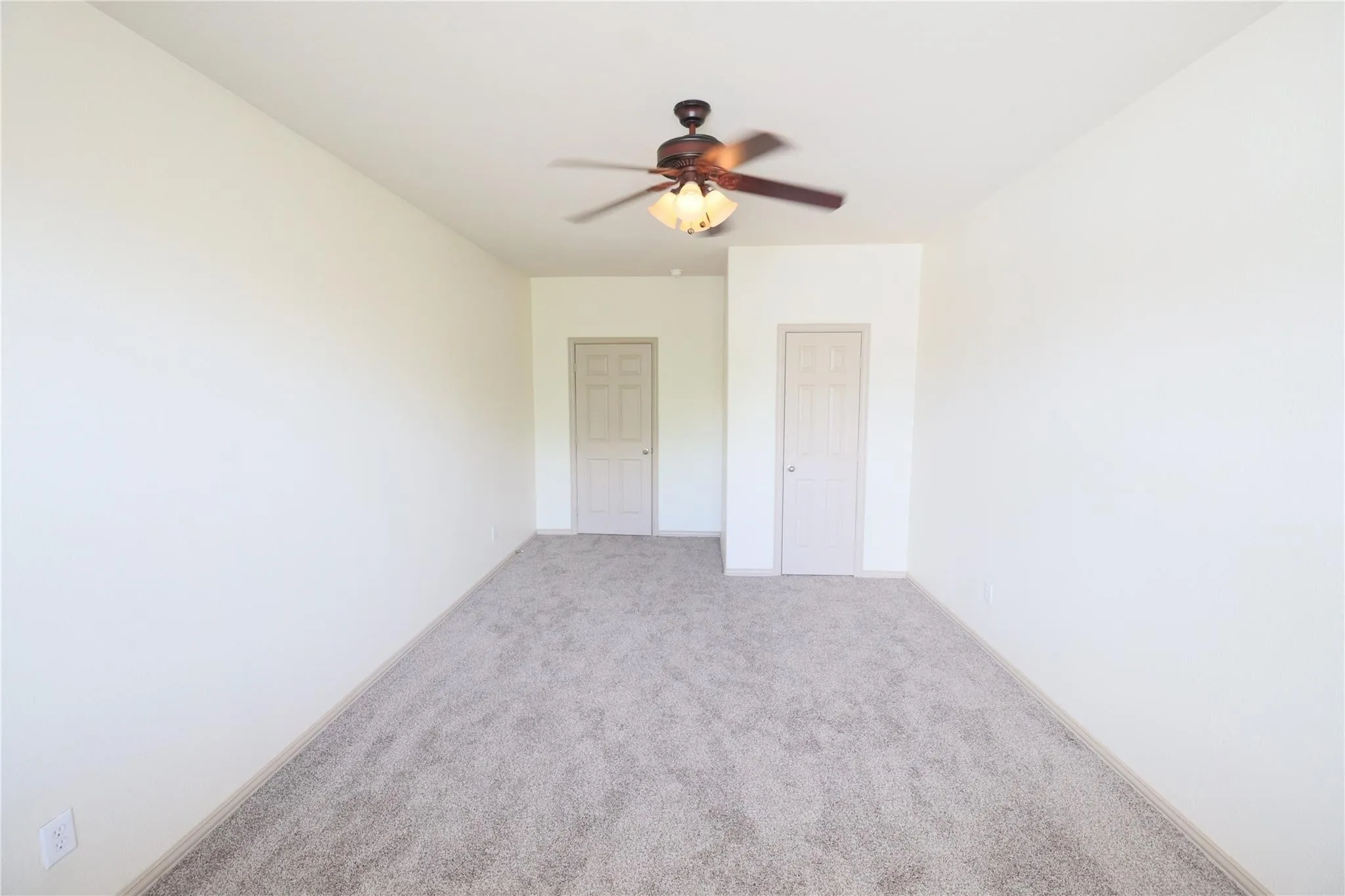 Neutral tone wall paint, textured carpeting, and a ceiling fan with integrated lighting