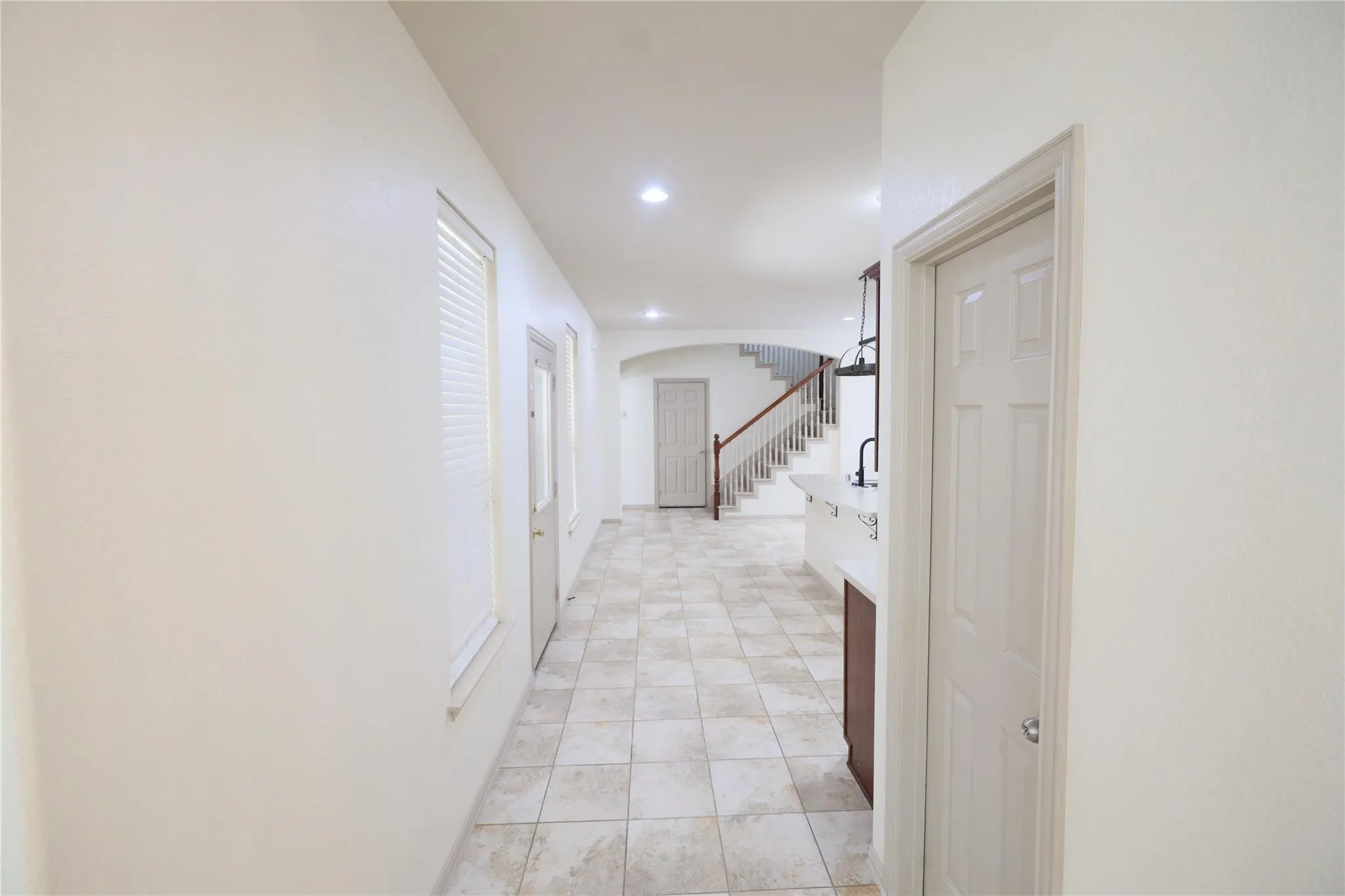 Hallway with light-toned tiled flooring, white walls, recessed lighting, and white paneled doors