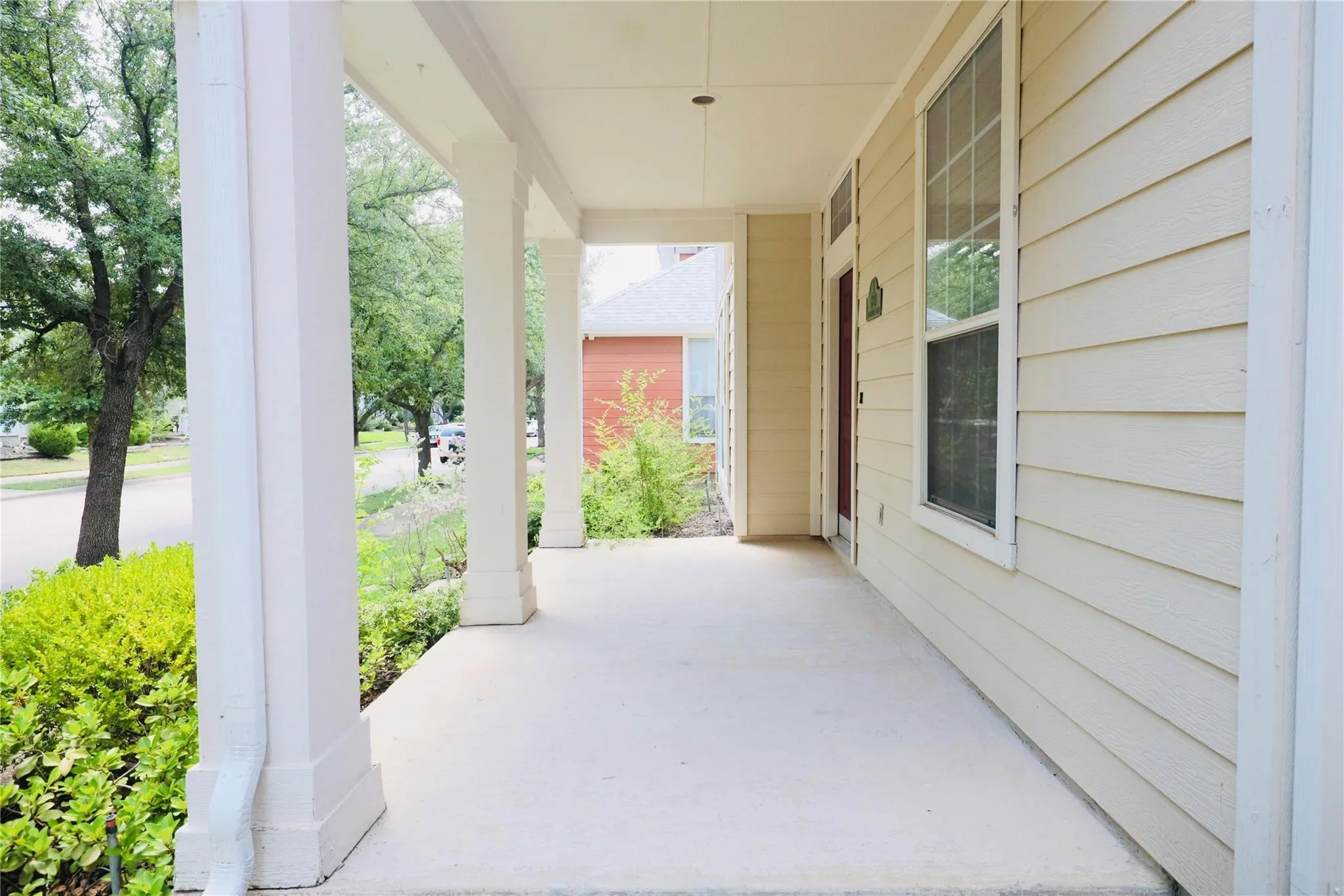 Expansive covered porch with concrete flooring and white support columns