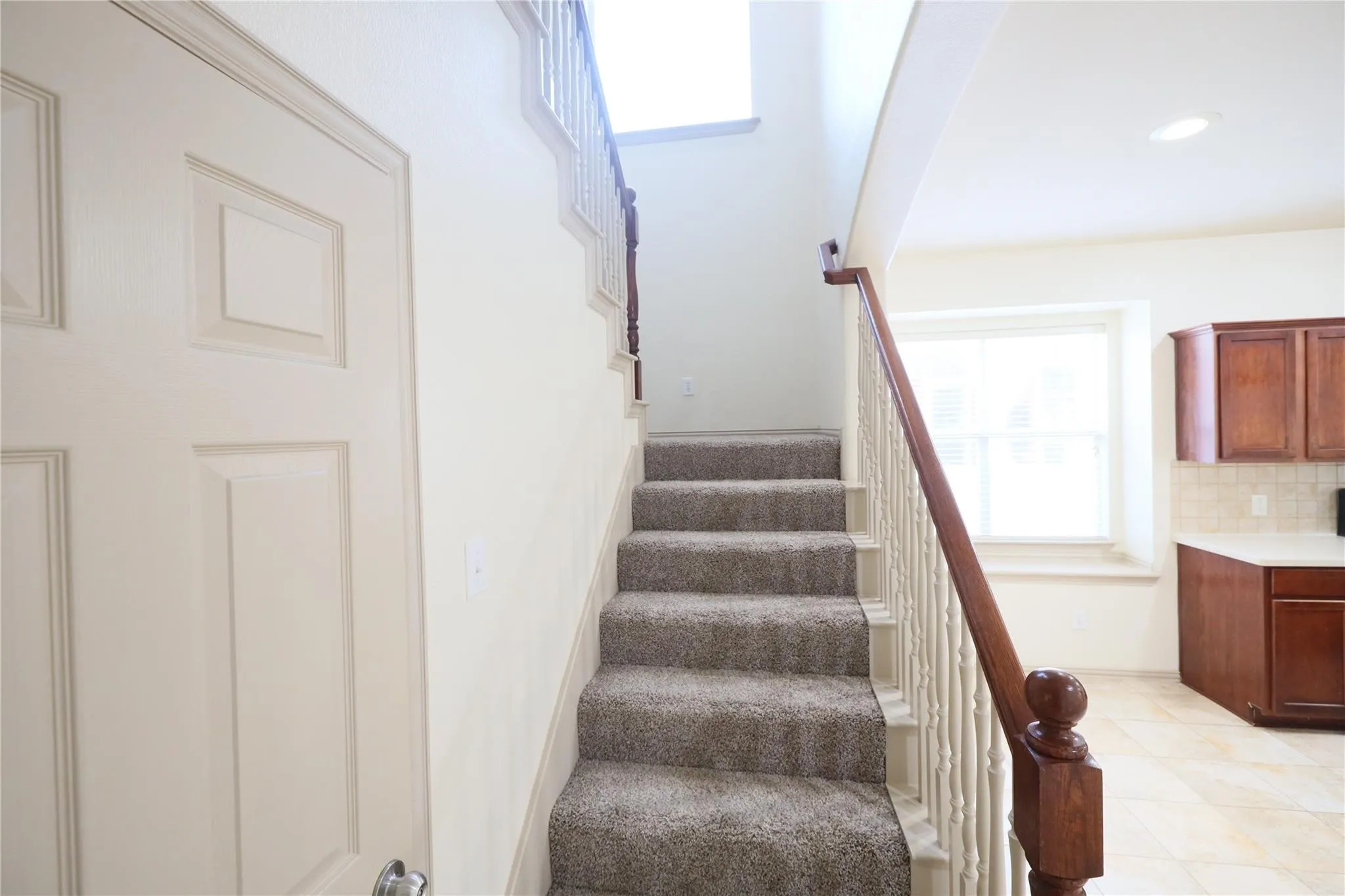 Carpeted staircase with a wood-finish handrail and white balusters