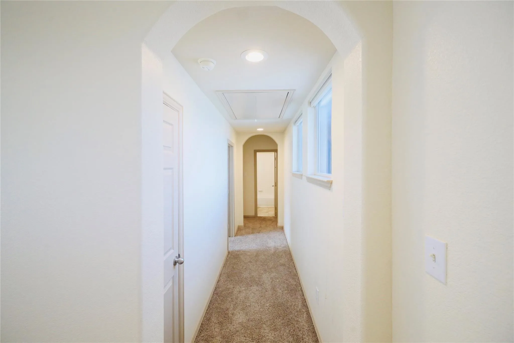 Arched hallway entry with recessed lighting, brown carpet flooring, and two transom windows