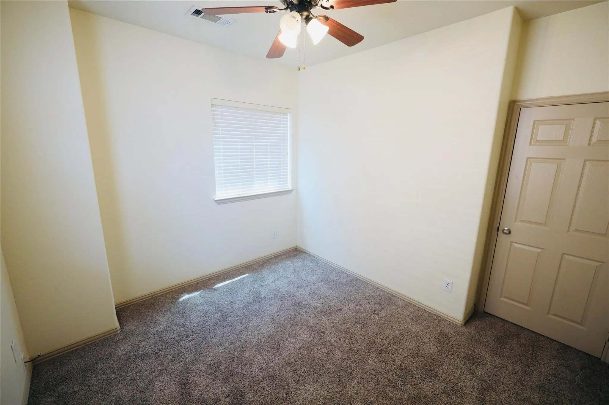 Neutral wall color, window with blinds, overhead ceiling fan, and carpeted flooring