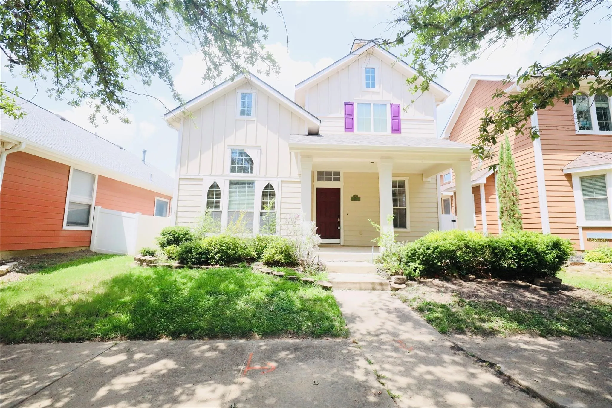 White siding exterior with a covered front porch, purple window shutters, arched window detailing, and a concrete walkway