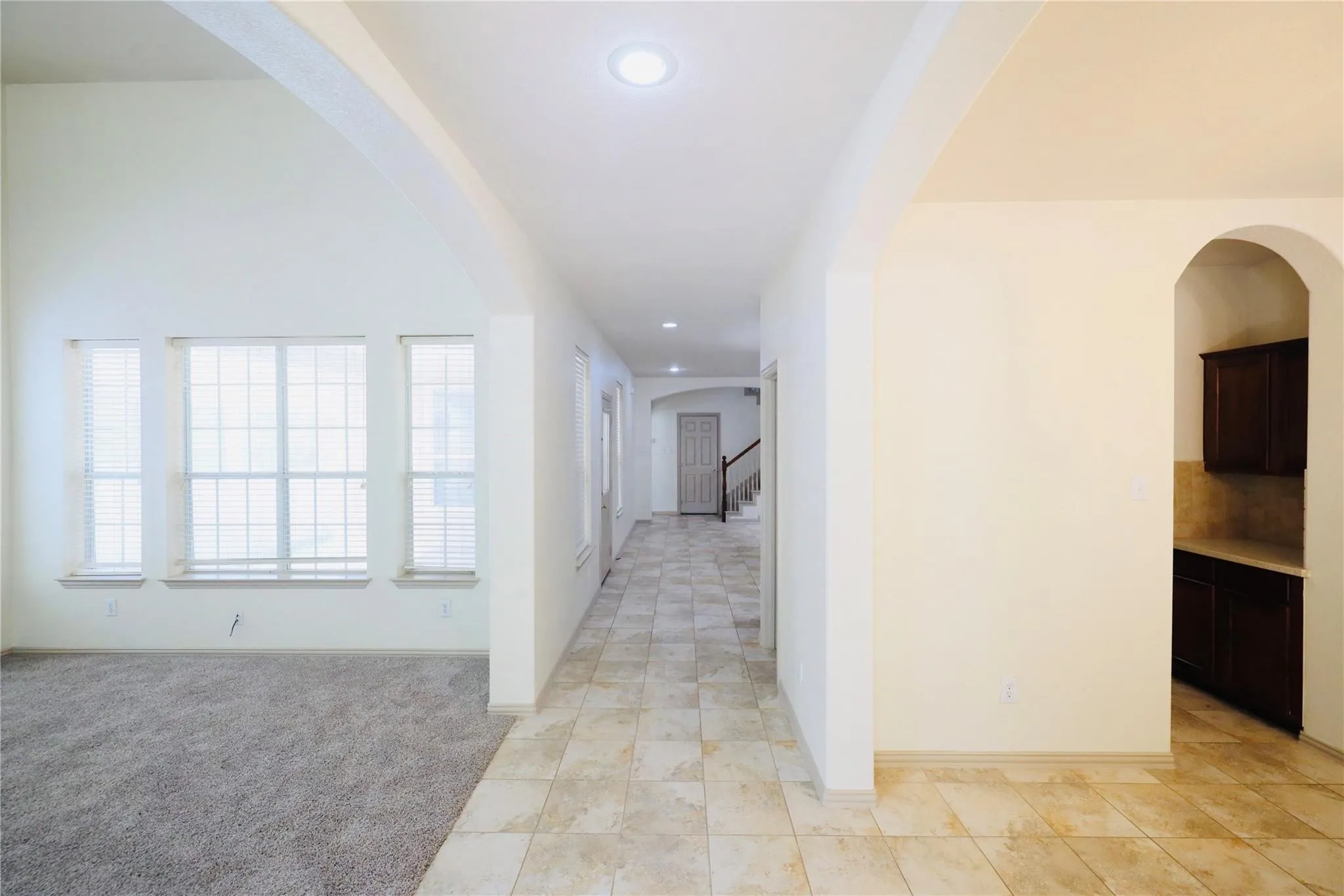 Vaulted ceilings, multiple windows, recessed lighting, tile flooring, and dark wood cabinetry