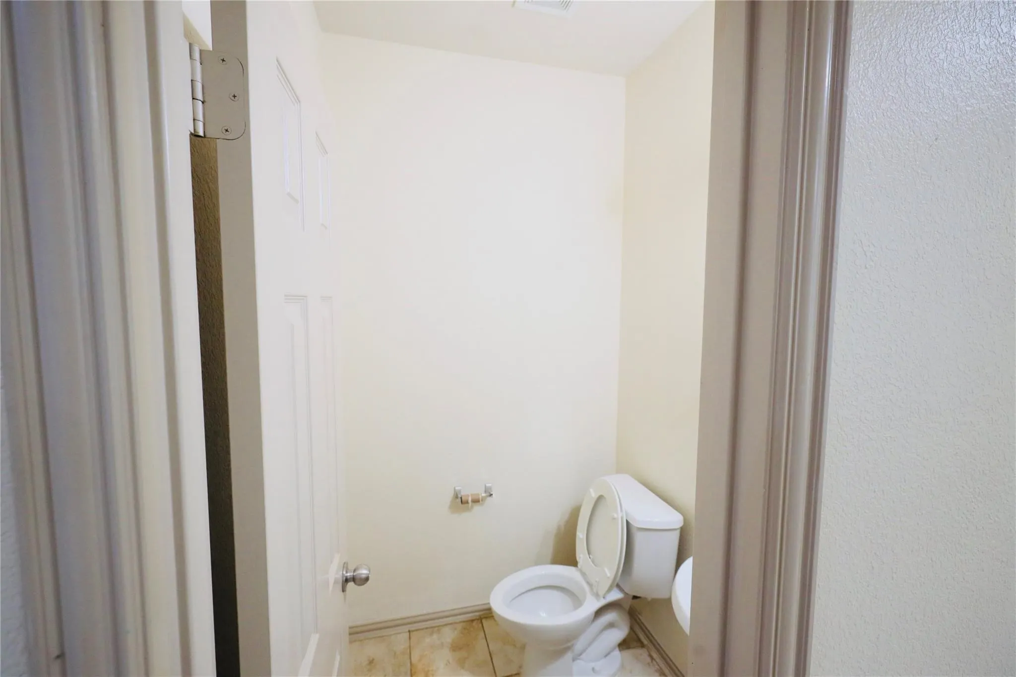 Powder room featuring a standard white toilet and a wall-mounted toilet paper holder