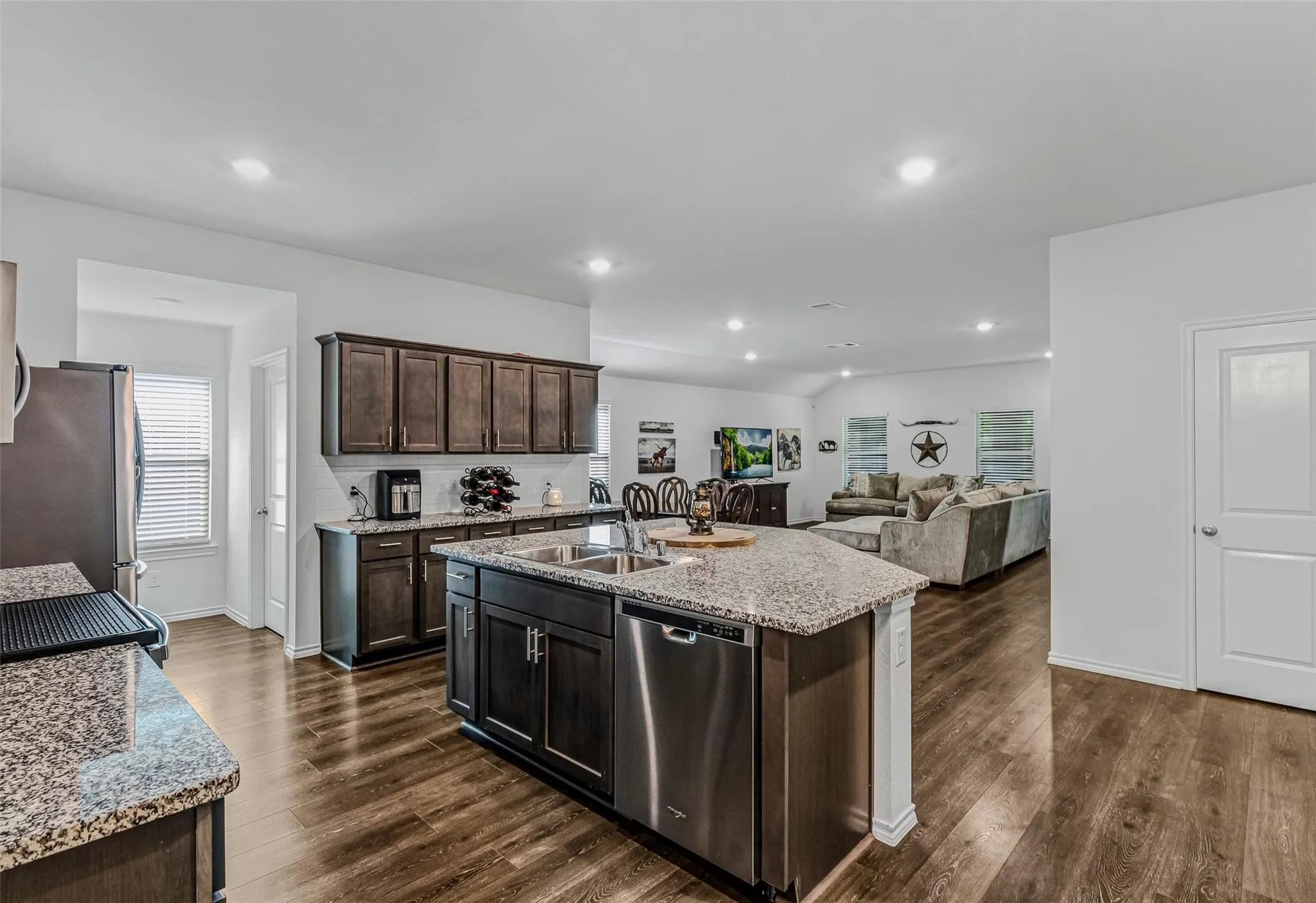 Kitchen with sink, a kitchen island with sink, dark wood-type flooring, and stainless steel appliances