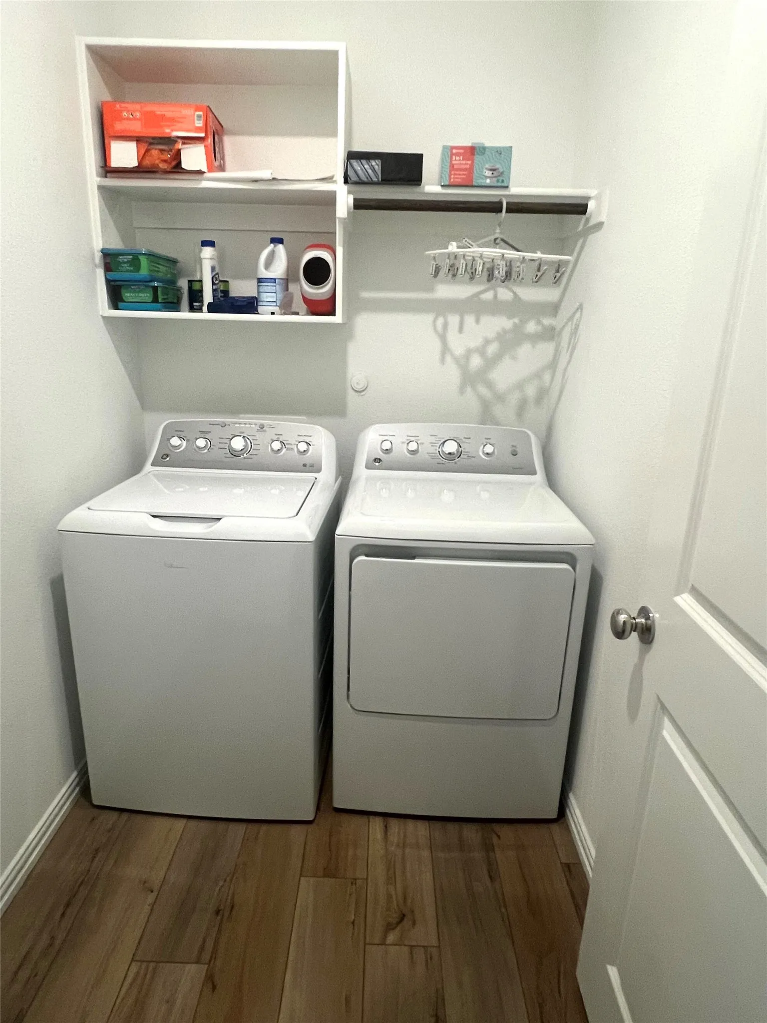Washroom with separate washer and dryer and hardwood / wood-style flooring