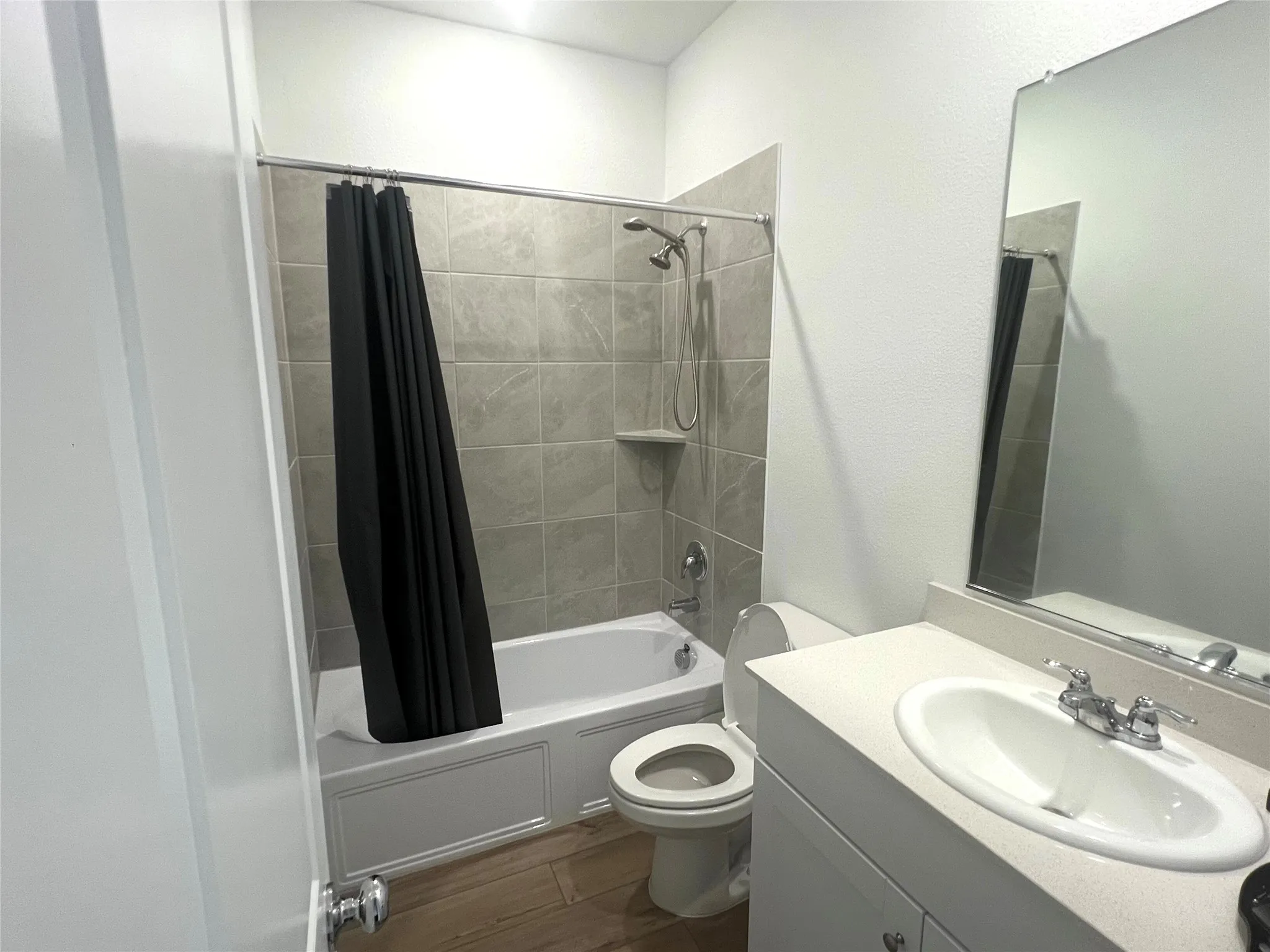 Full bathroom with large vanity, toilet, and shower / bath combo with shower curtain