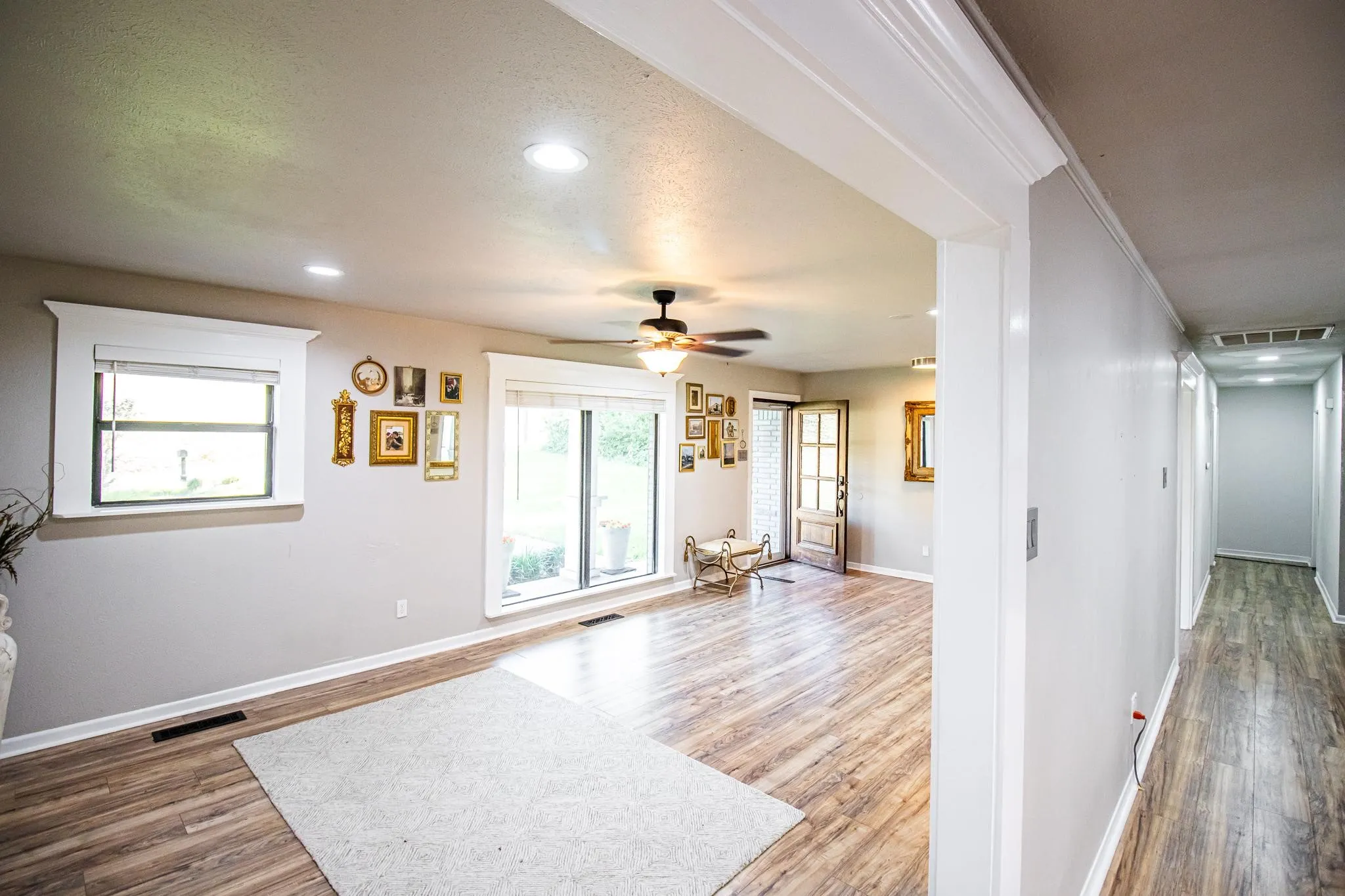 Open floor plan featuring wood-finish flooring, recessed lighting, ceiling fan, and window trim with wide molding