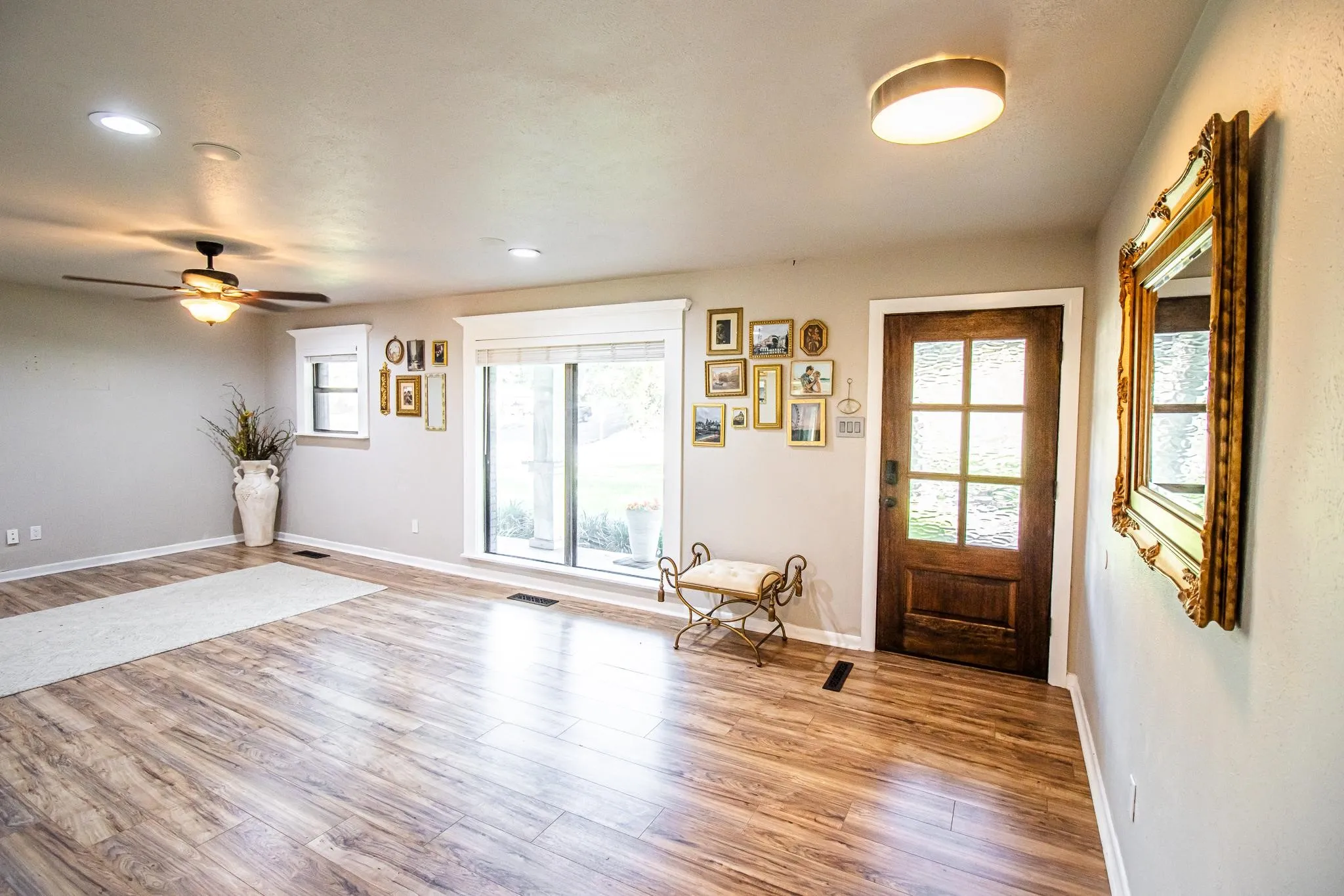 Wood-finish flooring, six-panel glass front door, recessed lighting, ceiling fan with light kit, and large windows with thick-profile trim