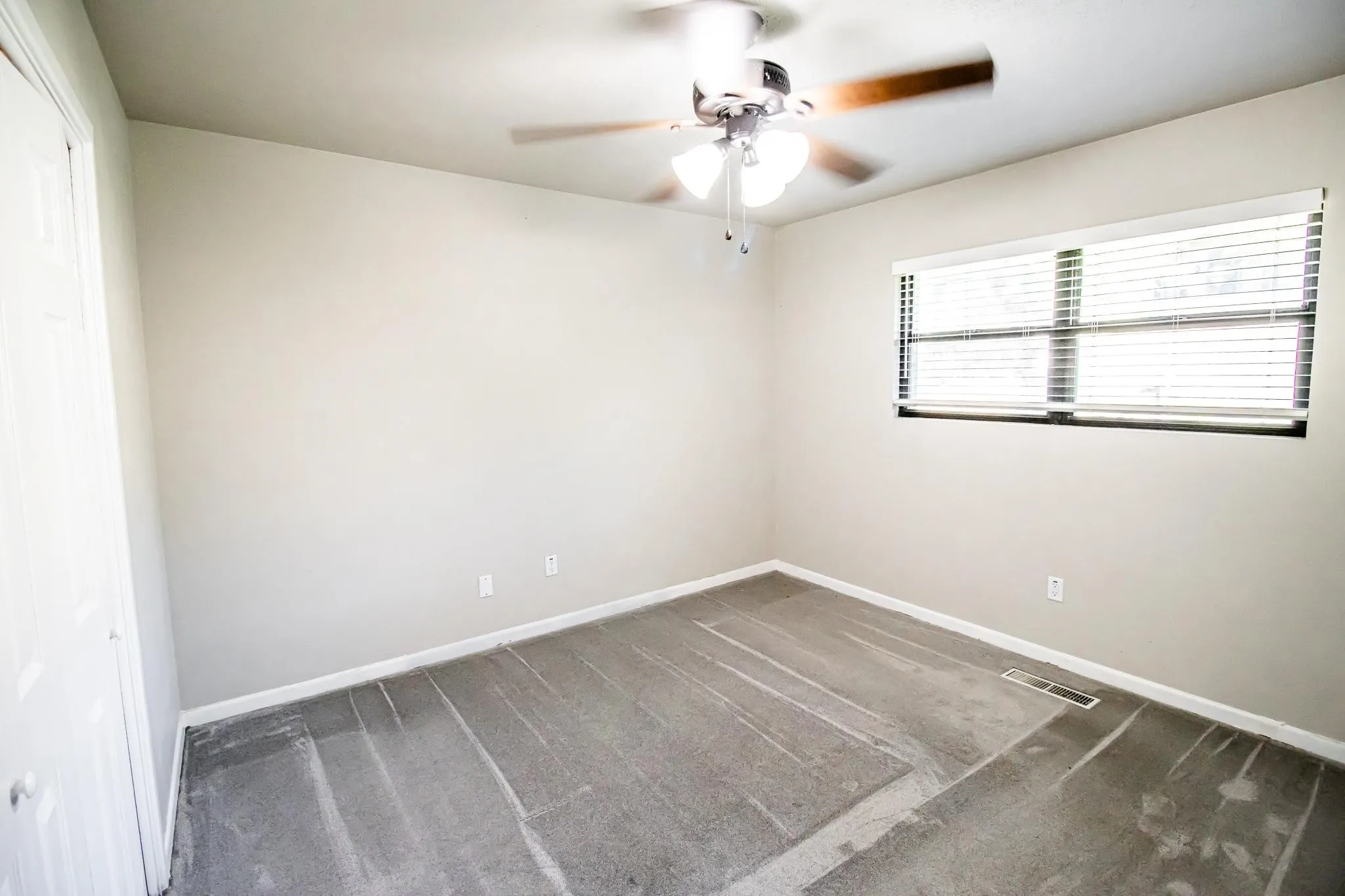 Room featuring wall-to-wall carpeting, neutral interior paint, a ceiling fan with integrated light fixture, and horizontal window blinds