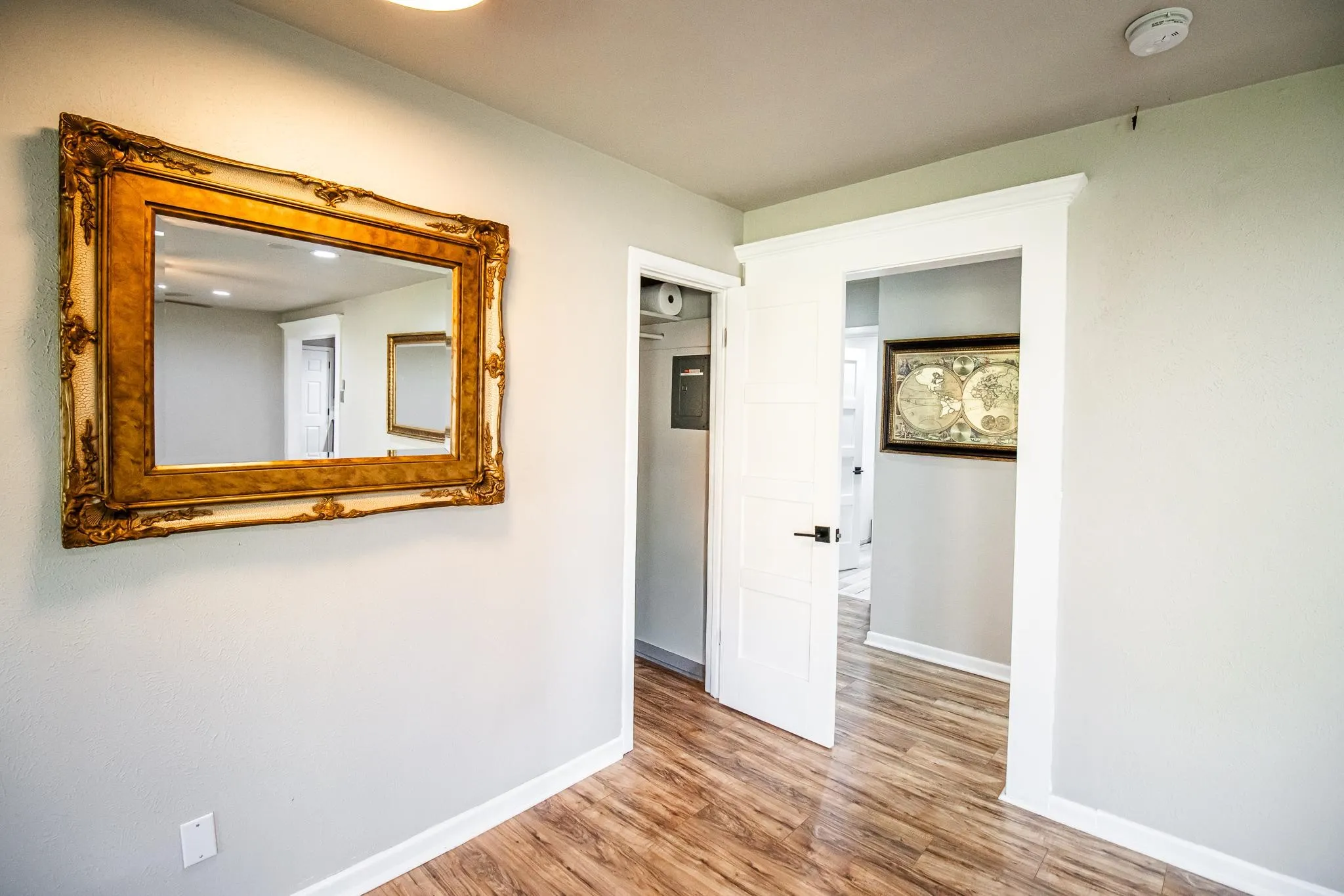 Four-panel interior door with matte black hardware, crisp white door casing, and wood-finish flooring