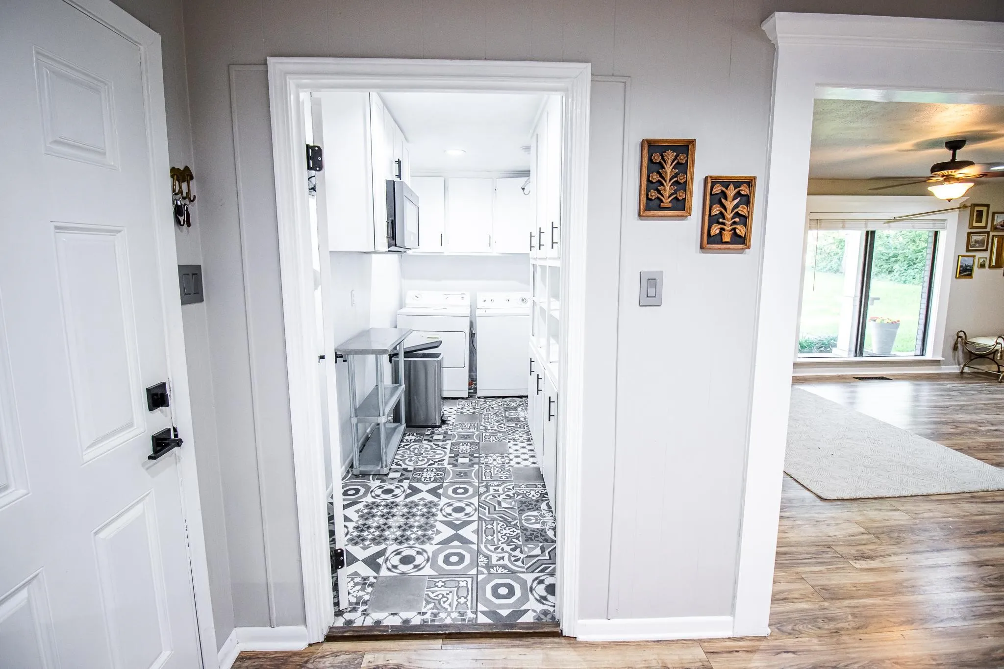 Utility room featuring geometric patterned floor tile, white built-in cabinetry, and wood-finish flooring