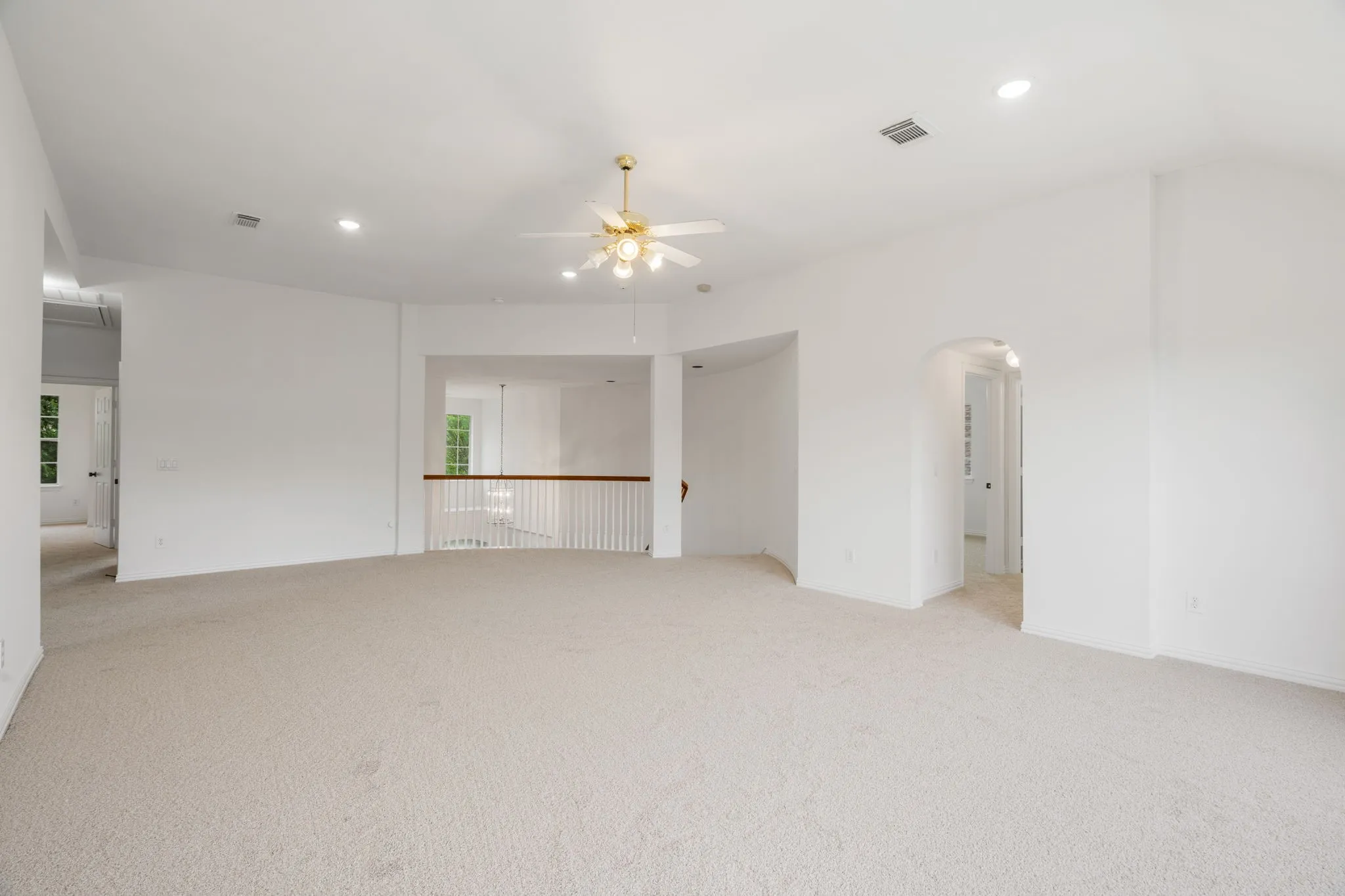 Expansive room featuring light-toned carpeting, vaulted ceiling, and recessed lighting