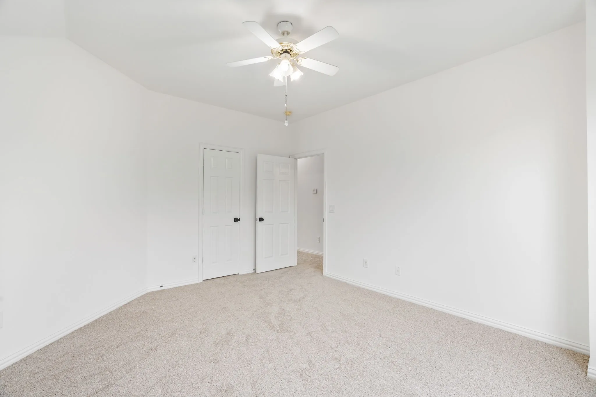 Neutral-toned carpeting with white walls and a ceiling fan with integrated lighting