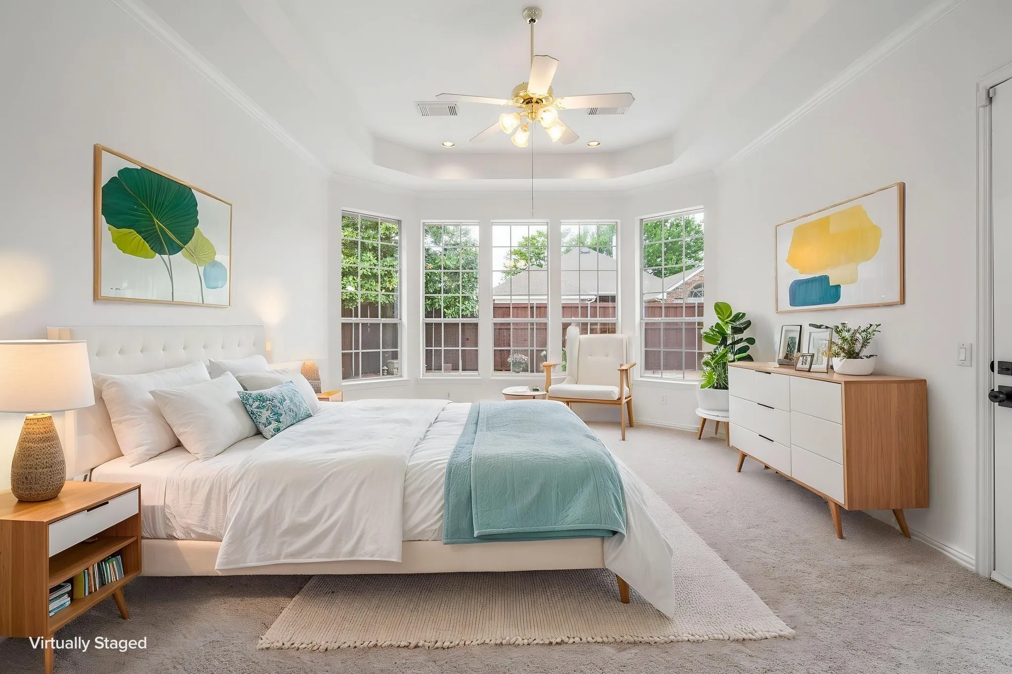 Tray ceiling with a ceiling fan, bay window with multiple panes, white walls, and a light-toned carpet