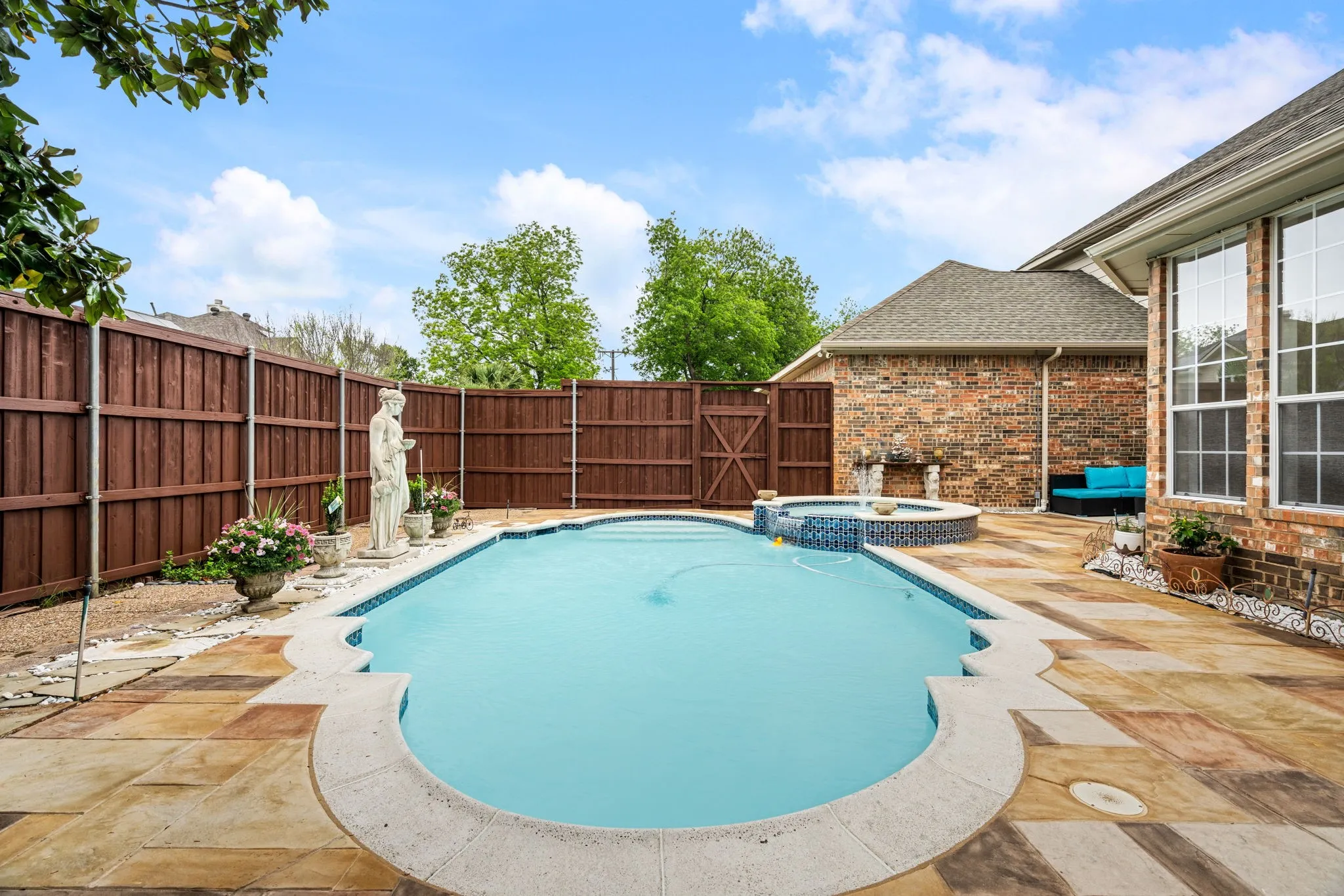 Backyard featuring a freeform swimming pool, integrated hot tub with mosaic tile, flagstone patio, and a privacy fence