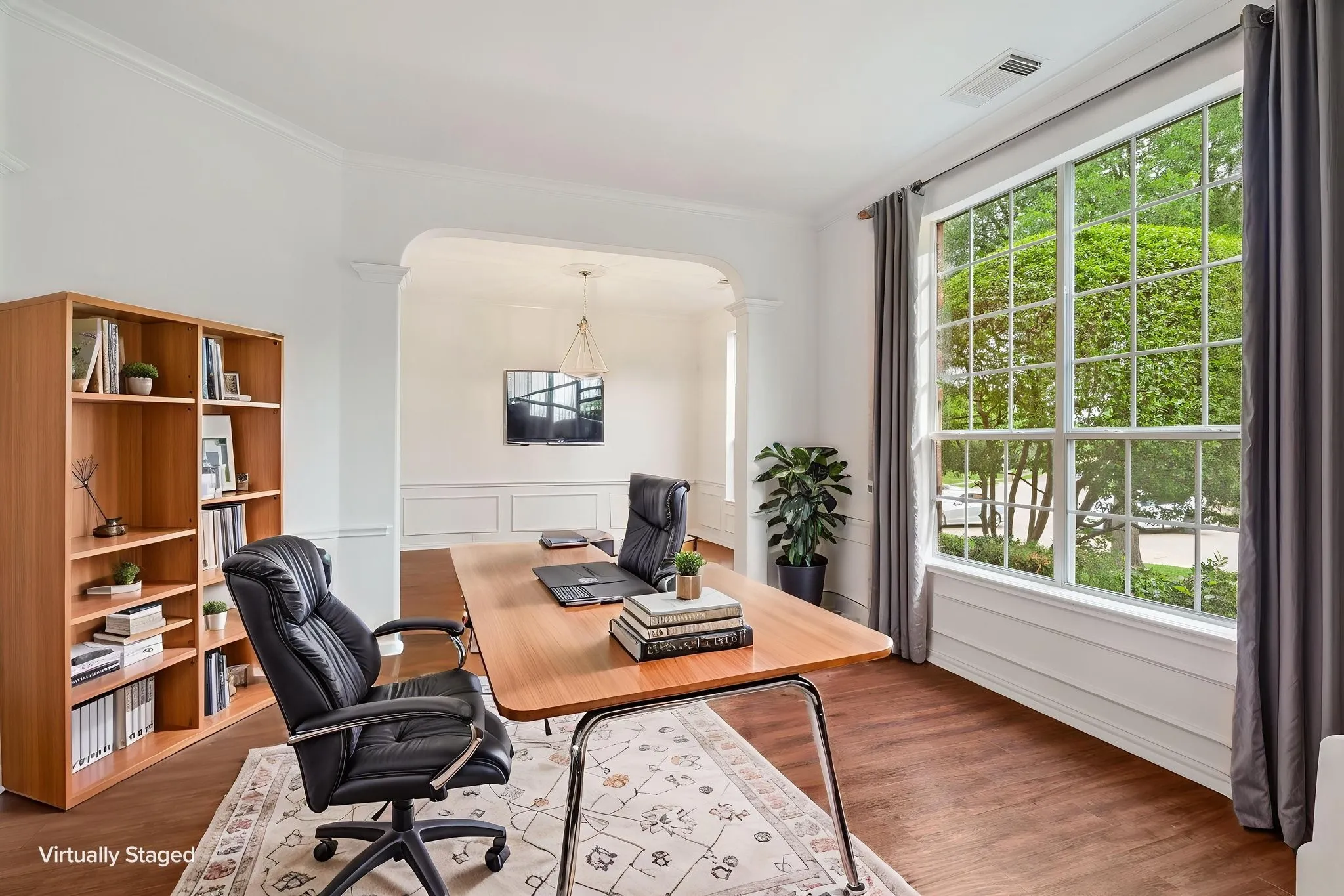 Hardwood-finish flooring, large multi-pane window, crown molding, arched entry, and wainscoting
