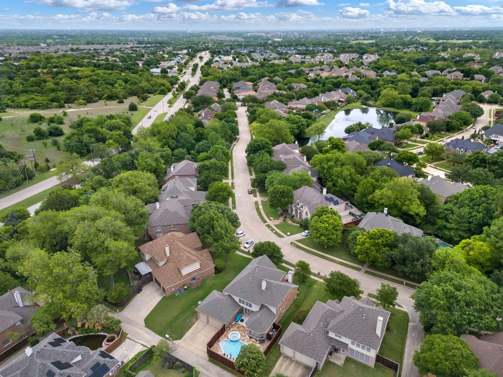Residential area featuring mature trees, a street network, and a pond