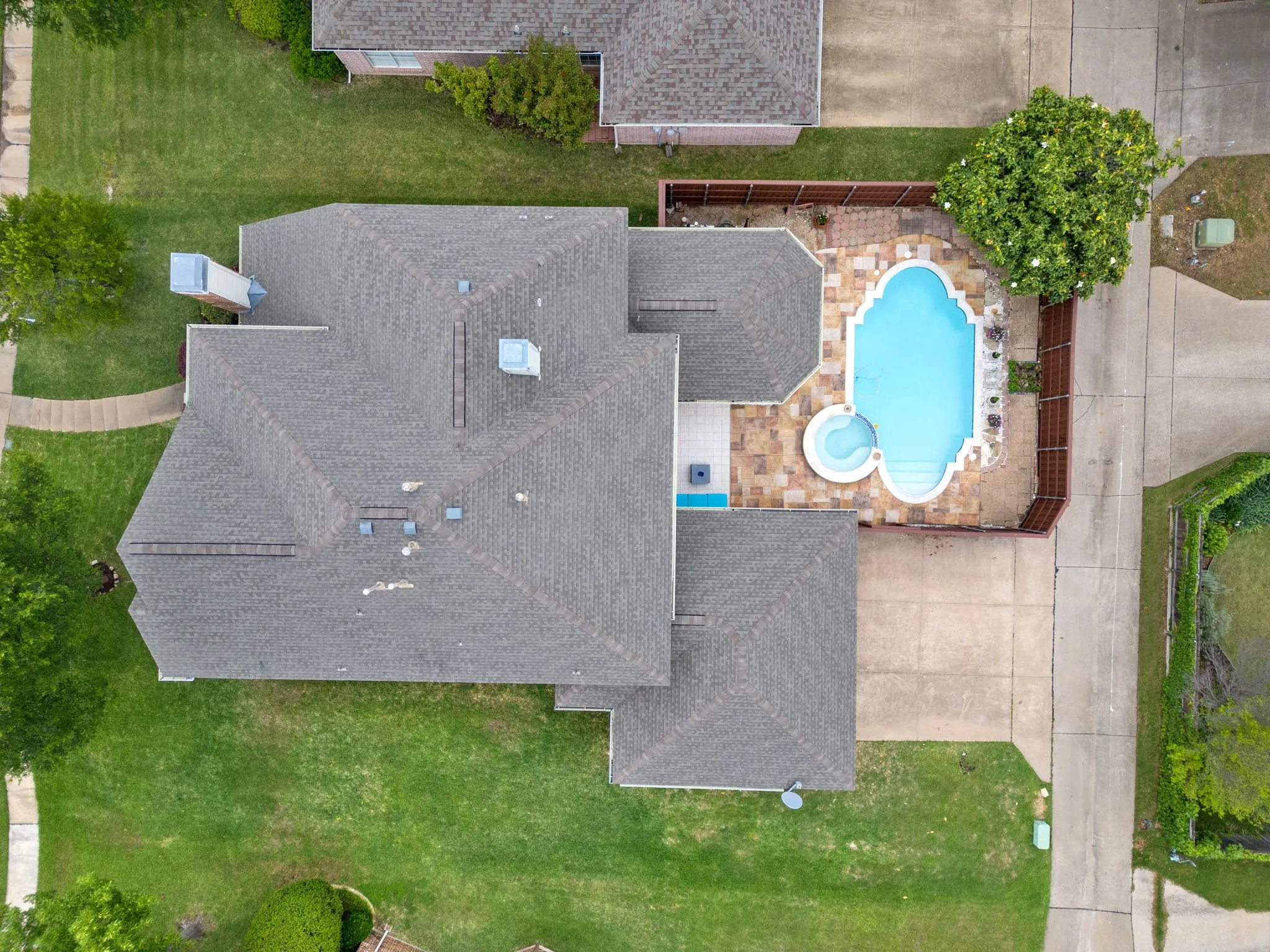 Shingle roof, swimming pool, spa, stone paver patio, and wood fencing