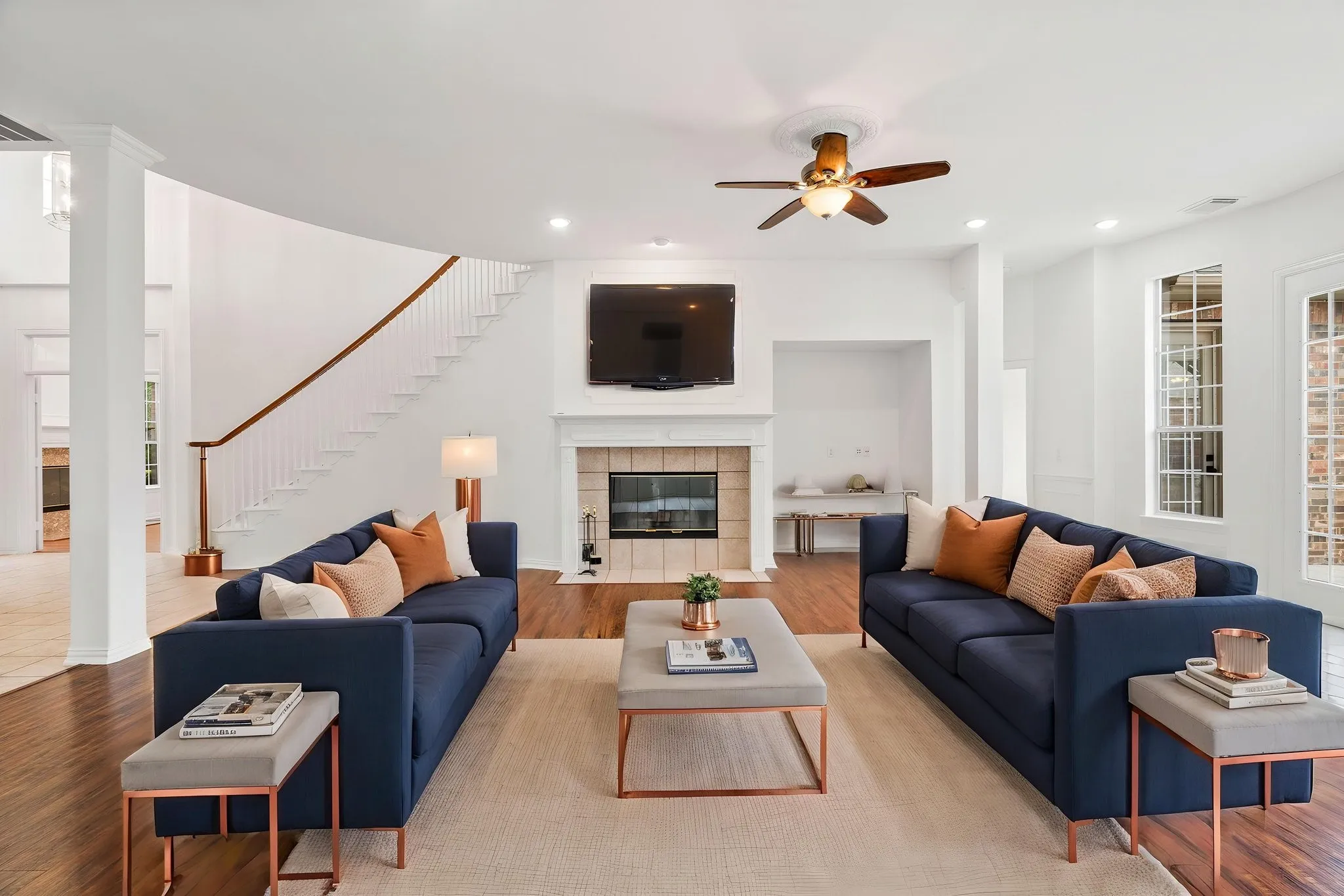 Hardwood-finish flooring throughout, fireplace with tile surround and mantel, recessed lighting, ceiling fan, and French doors