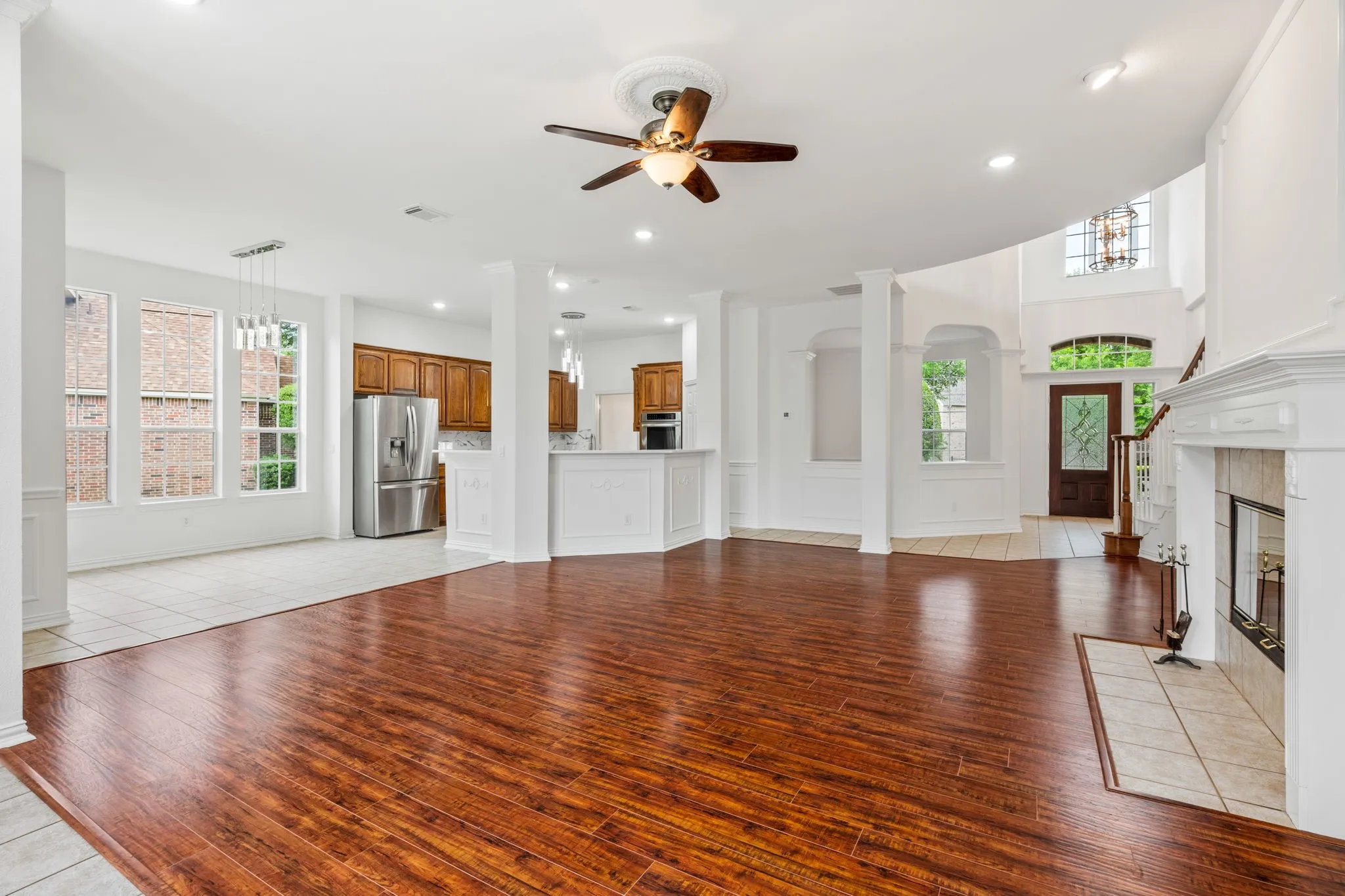 Spacious interior with wood-finish flooring, a ceiling fan, and a tiled fireplace