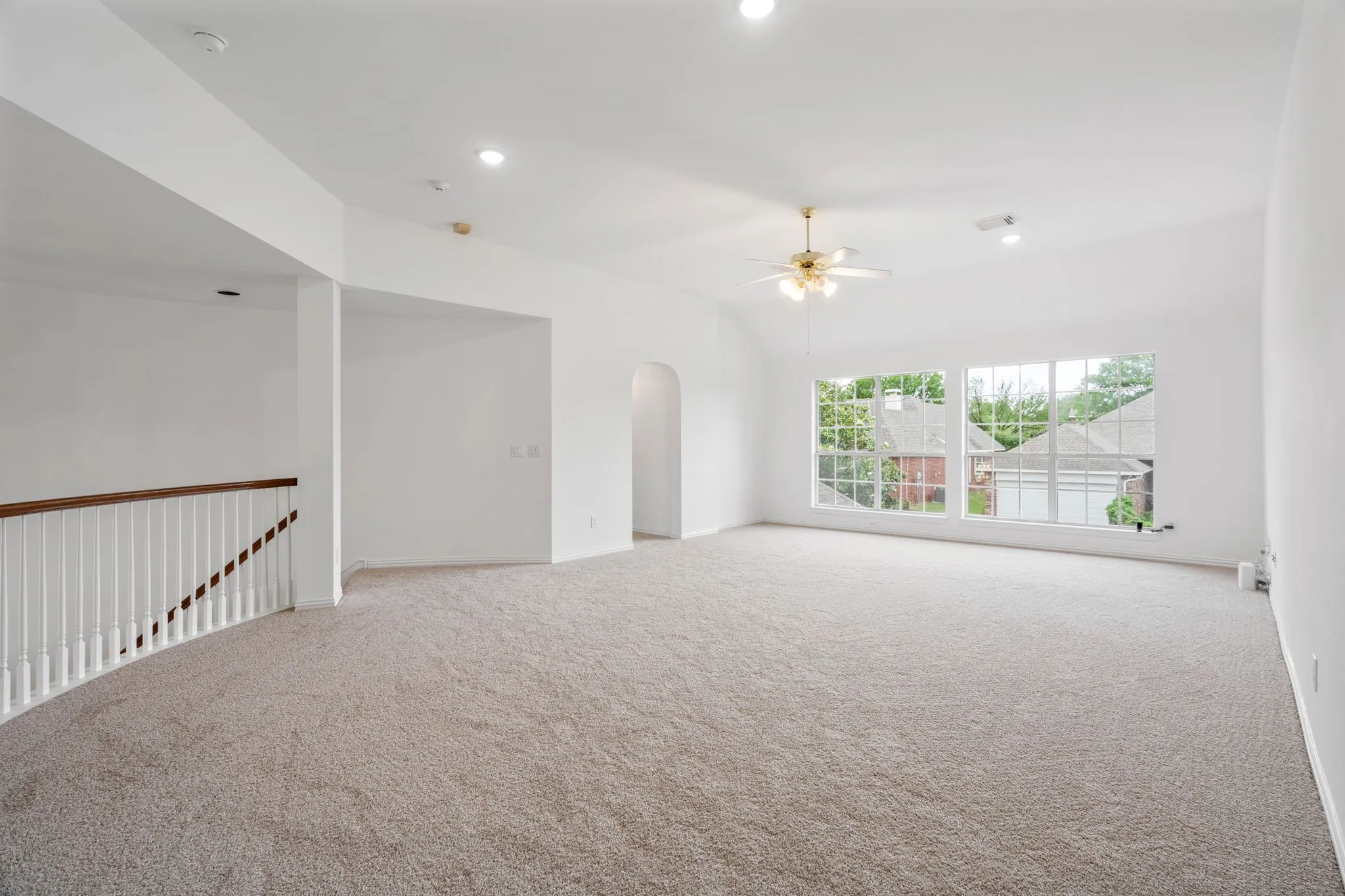 Vaulted ceiling, recessed lighting, ceiling fan, arched doorway, and carpet flooring