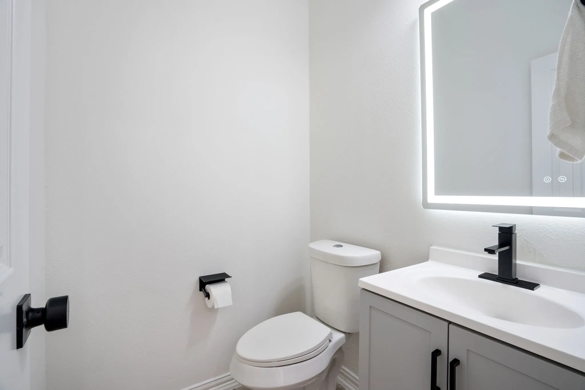 Contemporary bathroom vanity with a white integrated sink, matte black faucet, and a backlit mirror
