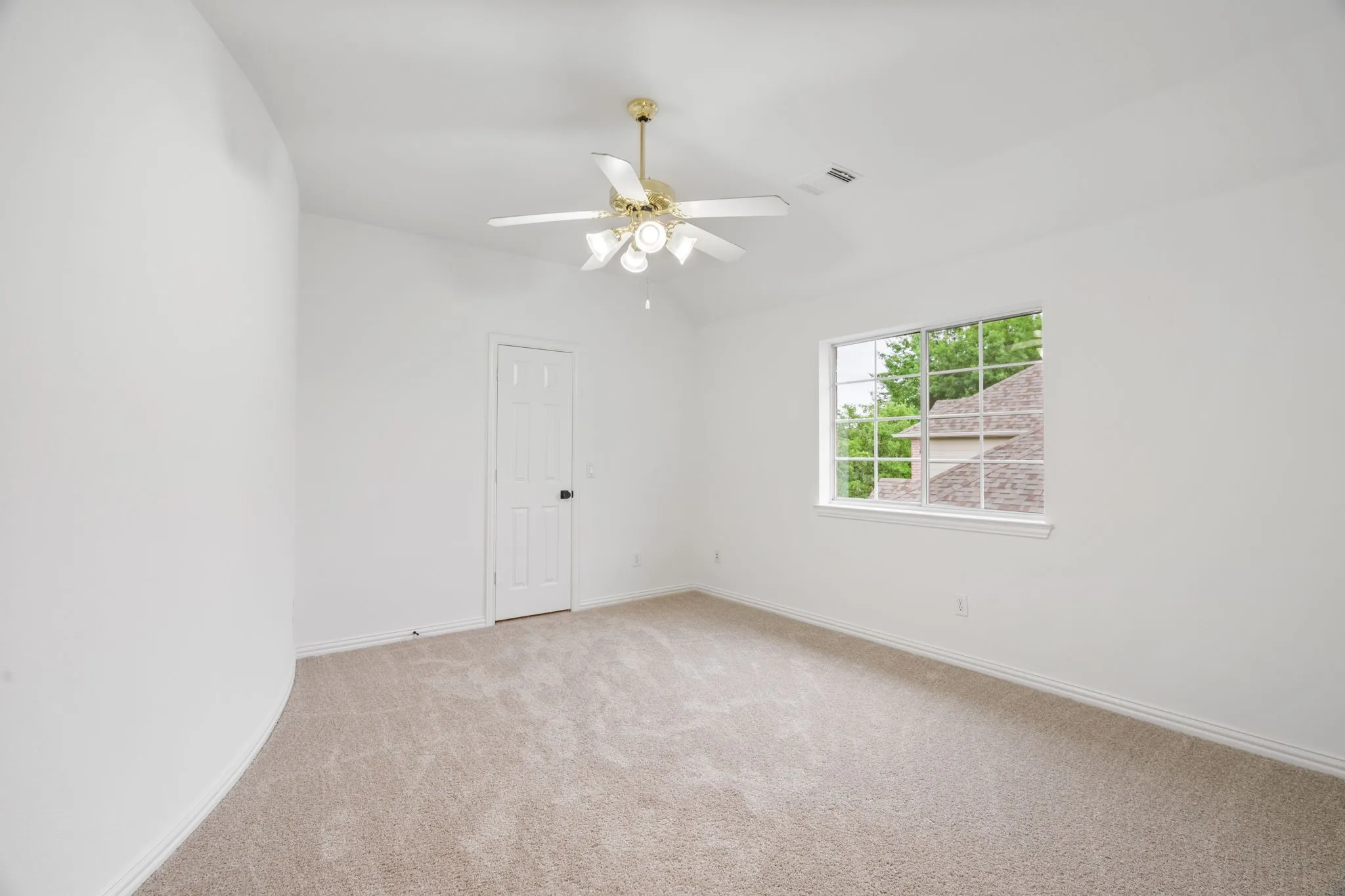 Carpeted flooring, vaulted ceiling, ceiling fan with light fixture, white interior door, and a multi-pane window