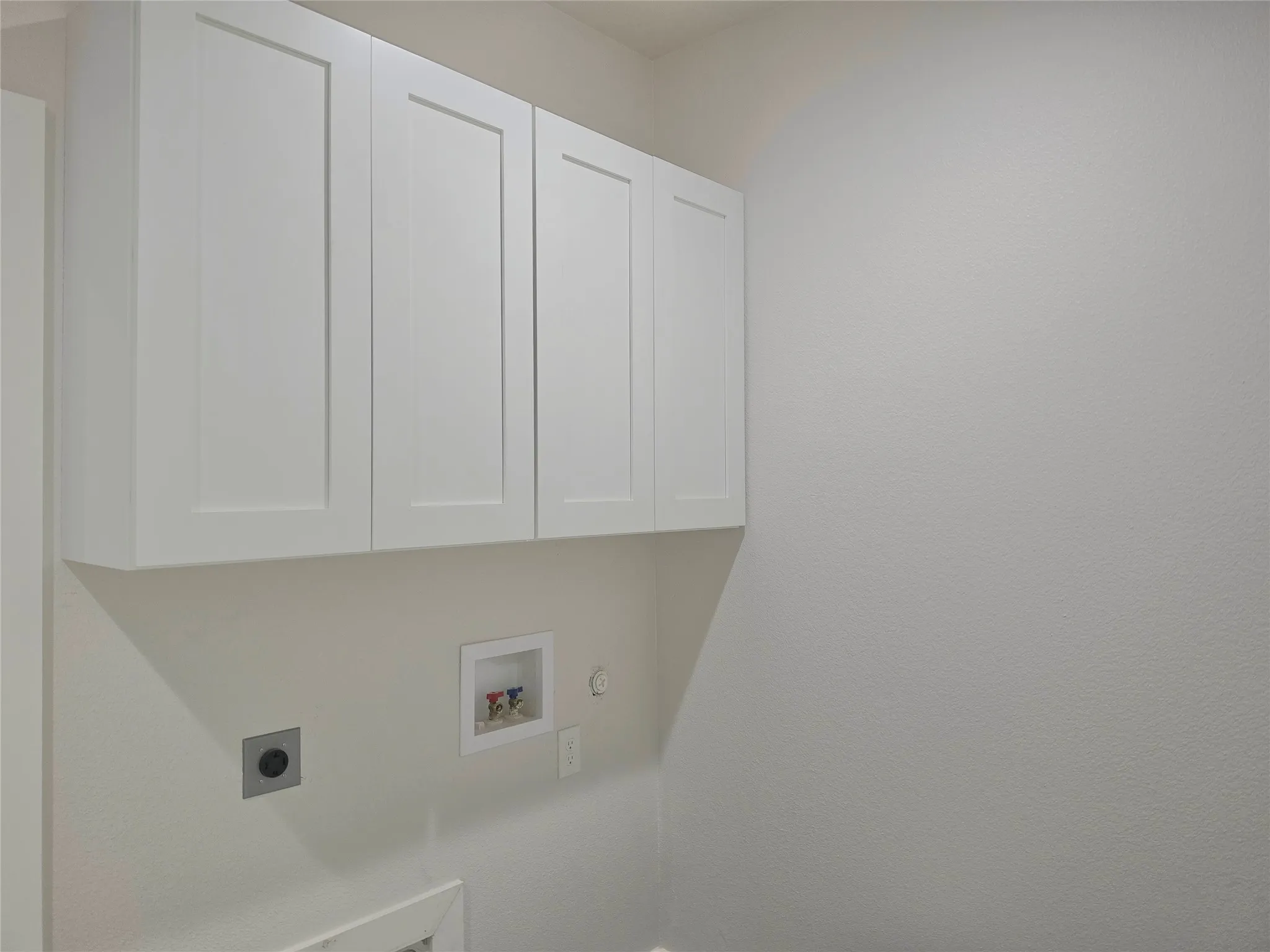 Shaker-style white cabinetry featuring flat-panel doors and polished hardware, complemented by a dedicated water supply box and electrical outlet