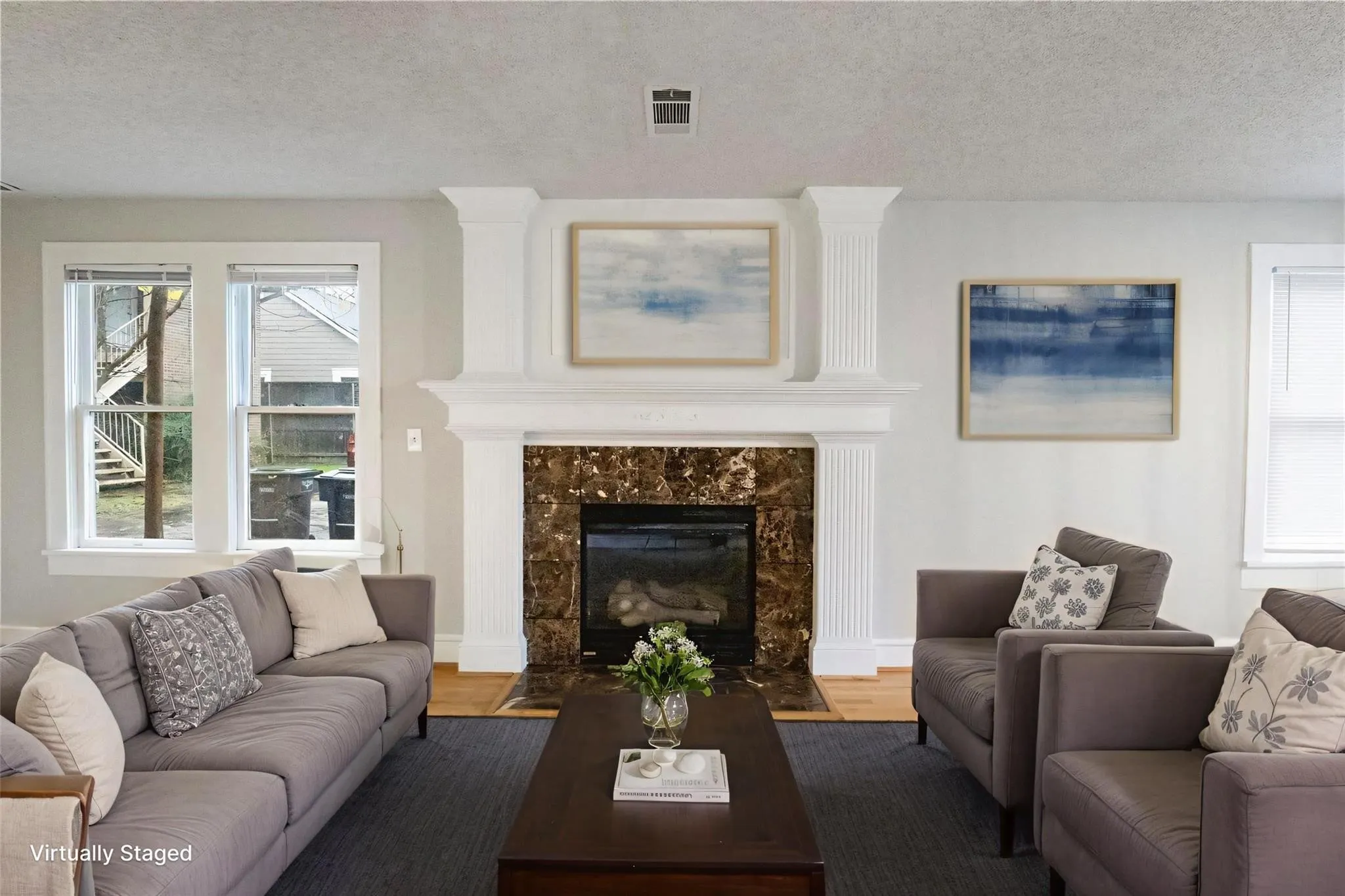 Fireplace featuring a stone-tiled surround, detailed crown molding, and a decorative mantel supported by fluted pilasters, accented by multi-pane windows with white trim