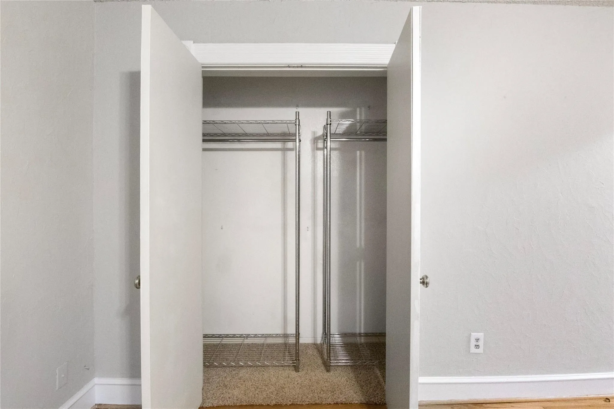 Double-door closet featuring integrated wire shelving and clothing rods