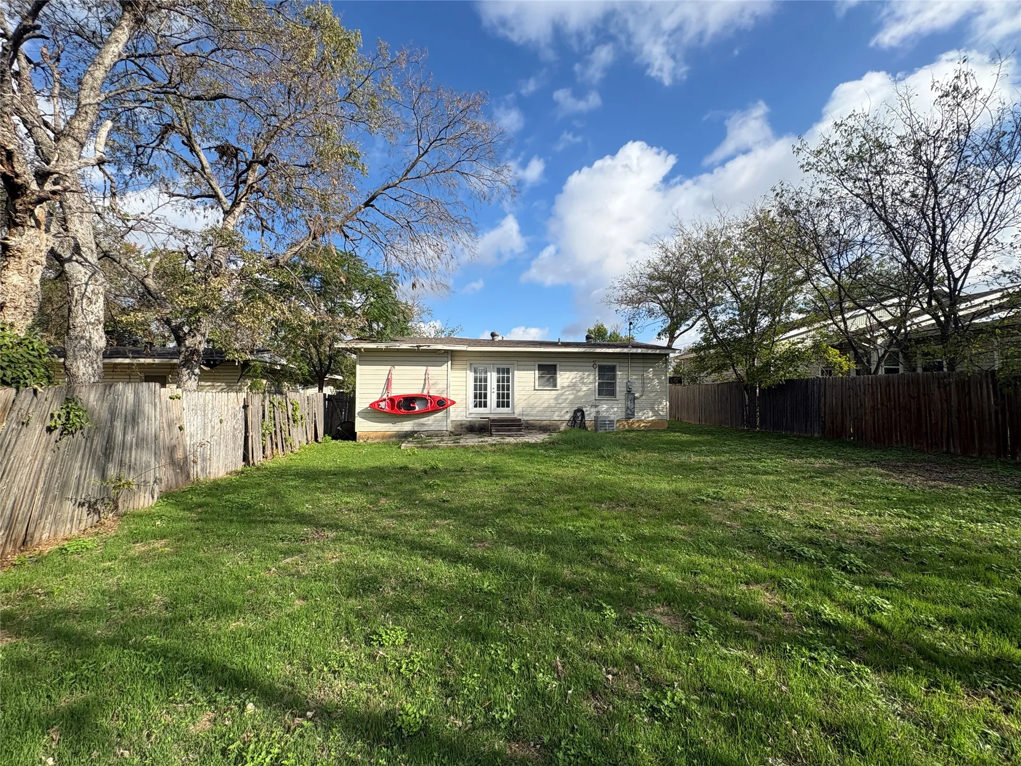 Expansive backyard featuring a level lawn, mature trees, and perimeter wood fencing