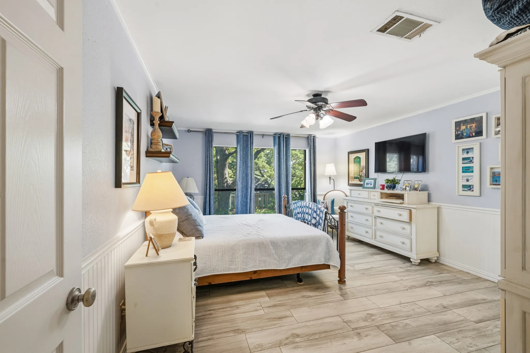 Large windows provide abundant natural light and showcase beautiful views of the surrounding trees. A ceiling fan adds comfort, while the generous floor space offers plenty of room for relaxing and unwinding.